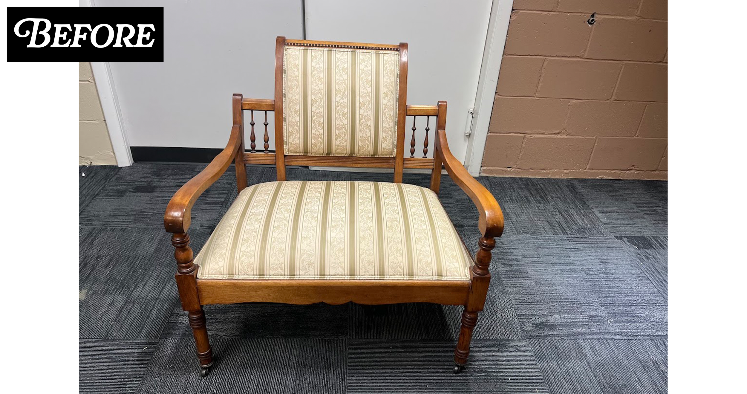 A vintage wooden armchair with a floral and striped fabric cushion on the seat and backrest. The chair is positioned in front of a beige wall with a brown brick section, on a dark gray carpeted floor.