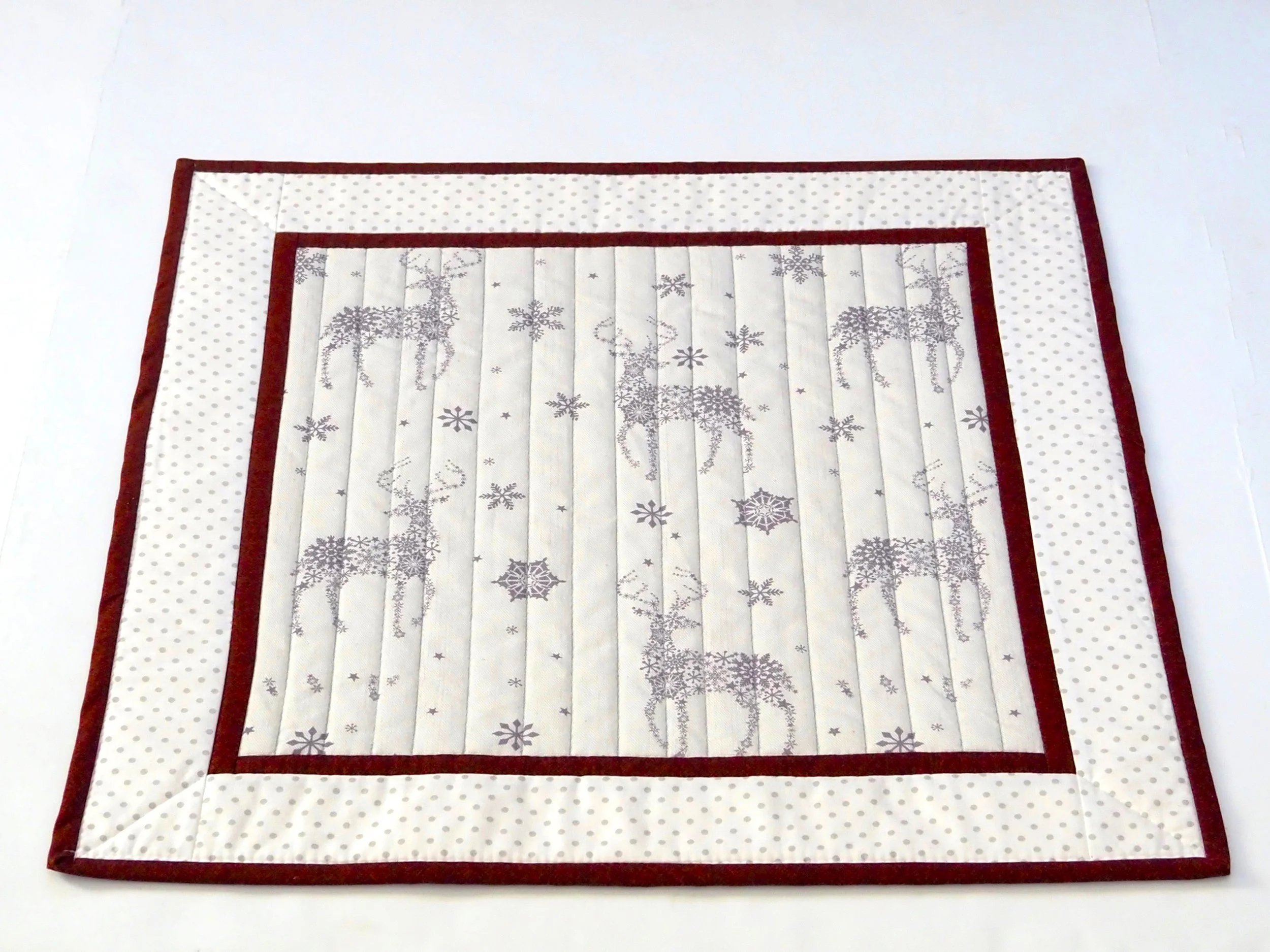 Detail shot of gray and white reindeer and red border holiday runner