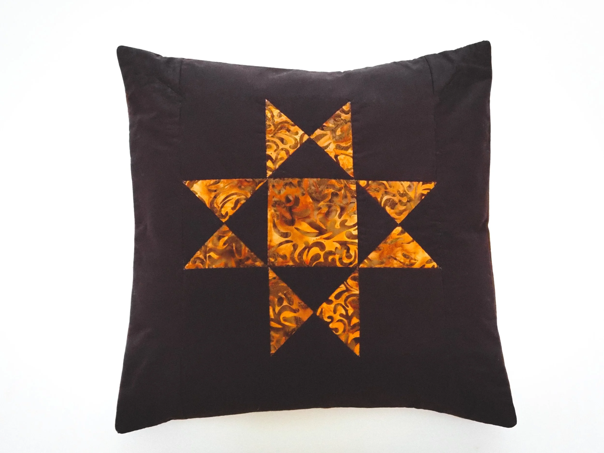 Brown and orange star quilted pillow cover styled on sofa