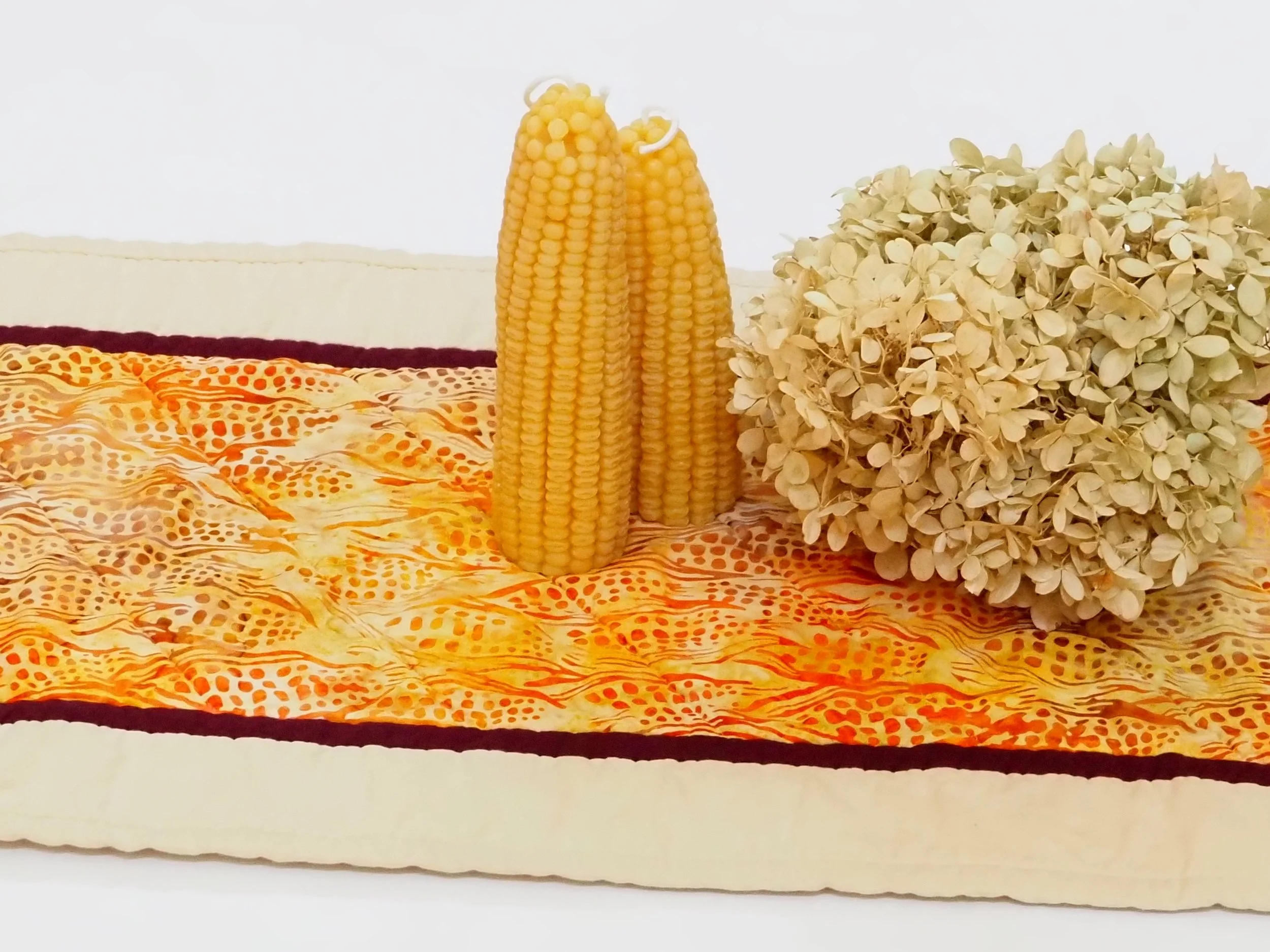 Bring the rich, inviting warmth of autumn to your dining space with this handcrafted Indian Corn Quilted Table Runner. Featuring a stunning batik center print framed by deep burgundy and soft khaki borders.