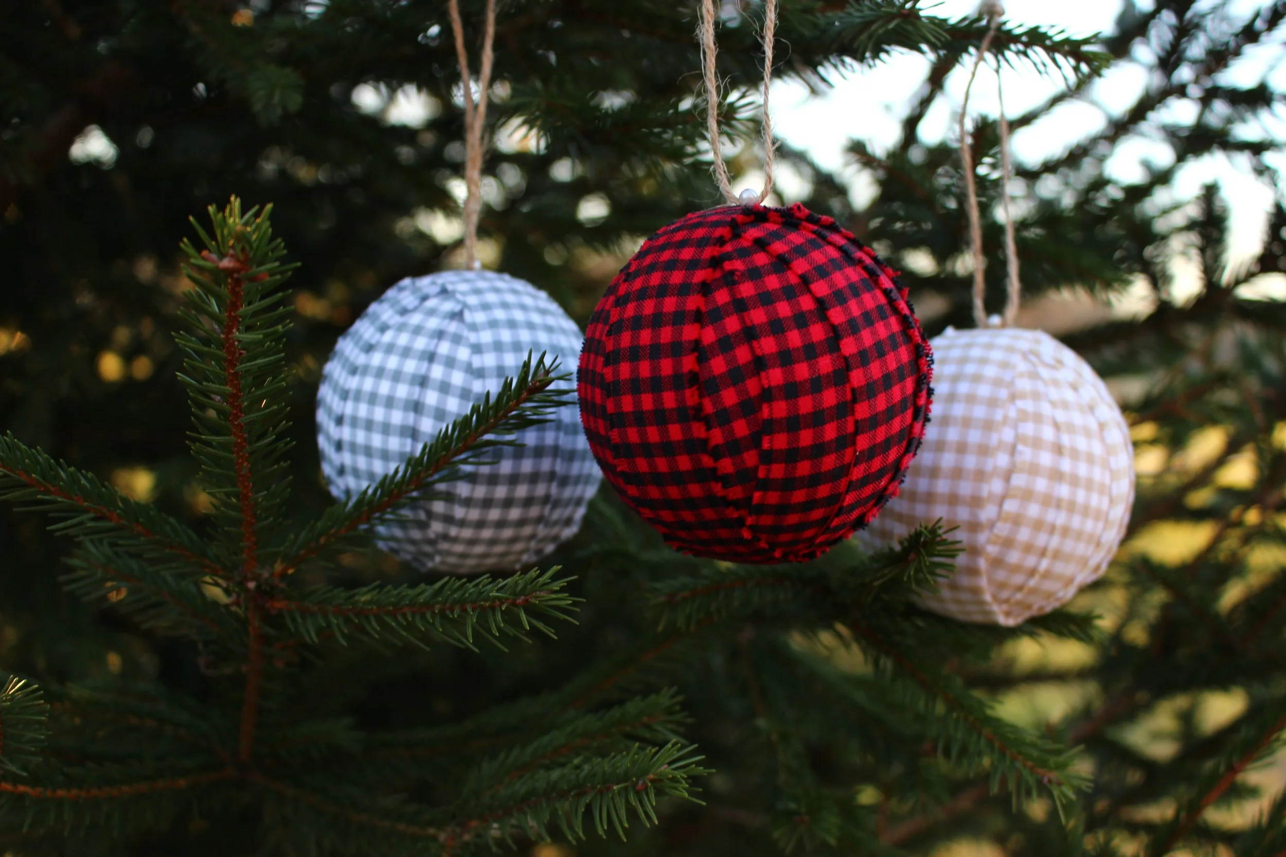 Red and black buffalo check plaid Christmas ball ornament hanging on tree branch
