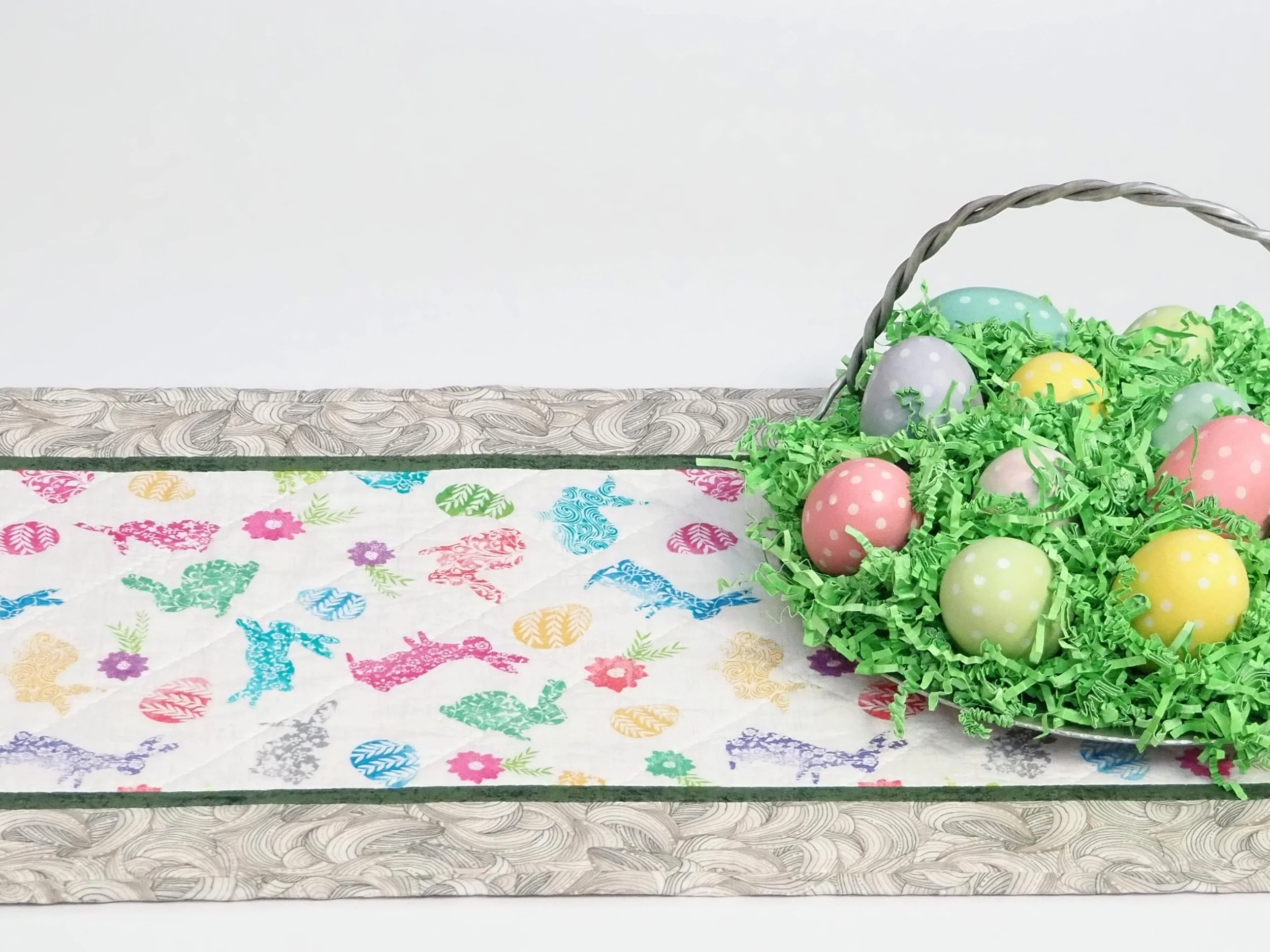 Handmade quilted table runner with pastel bunny pattern on a wooden dining table