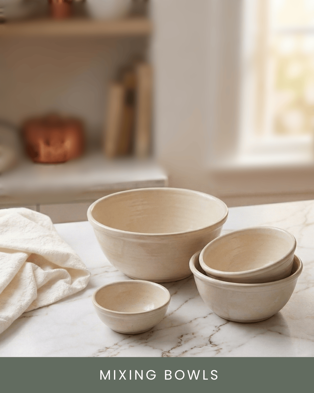 Set of beige mixing bowls of various sizes arranged on a white marble countertop with a cloth nearby, in a bright kitchen.
