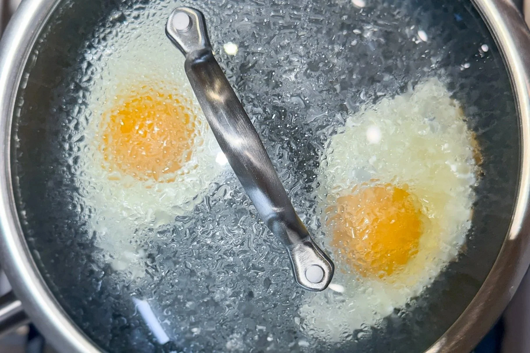 two eggs in a pan being steamed-fried