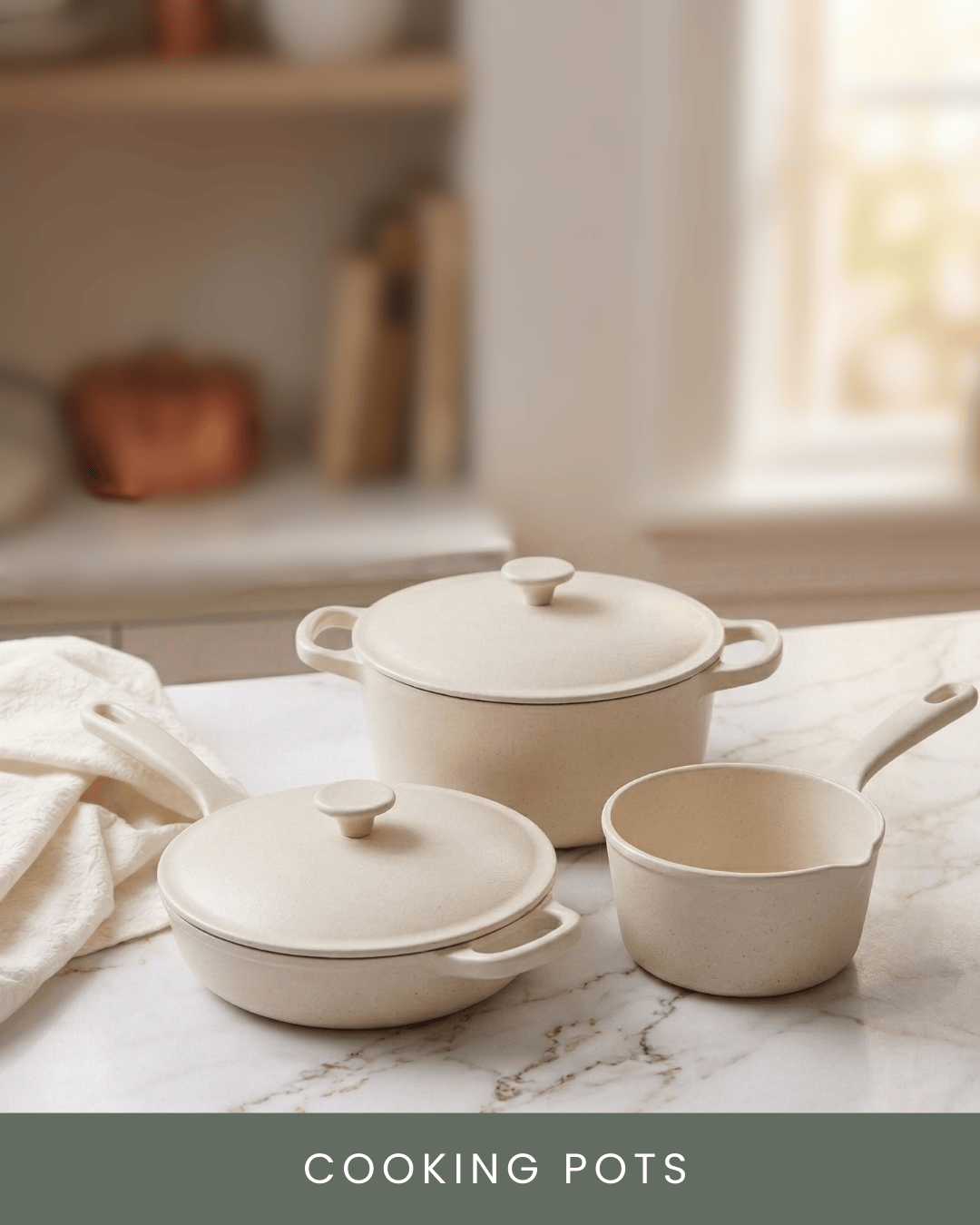 Cream-colored cooking pots with lids and a small saucepan on a marble countertop in a bright kitchen.