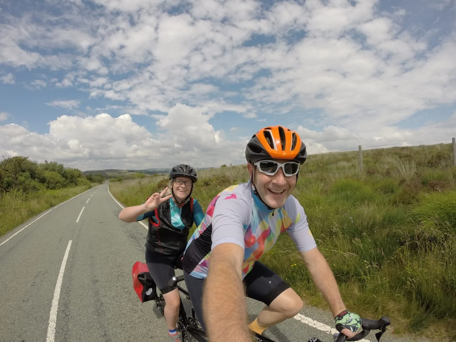 Image shows Jo and her husband riding their tandem in the sunshine.