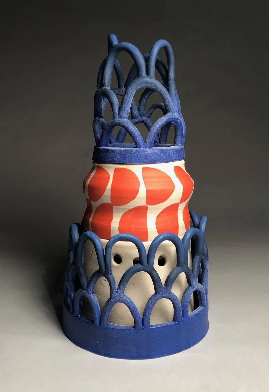 Decorative ceramic piece resembling a layered cake with blue lattice structures and a red and white patterned middle section.