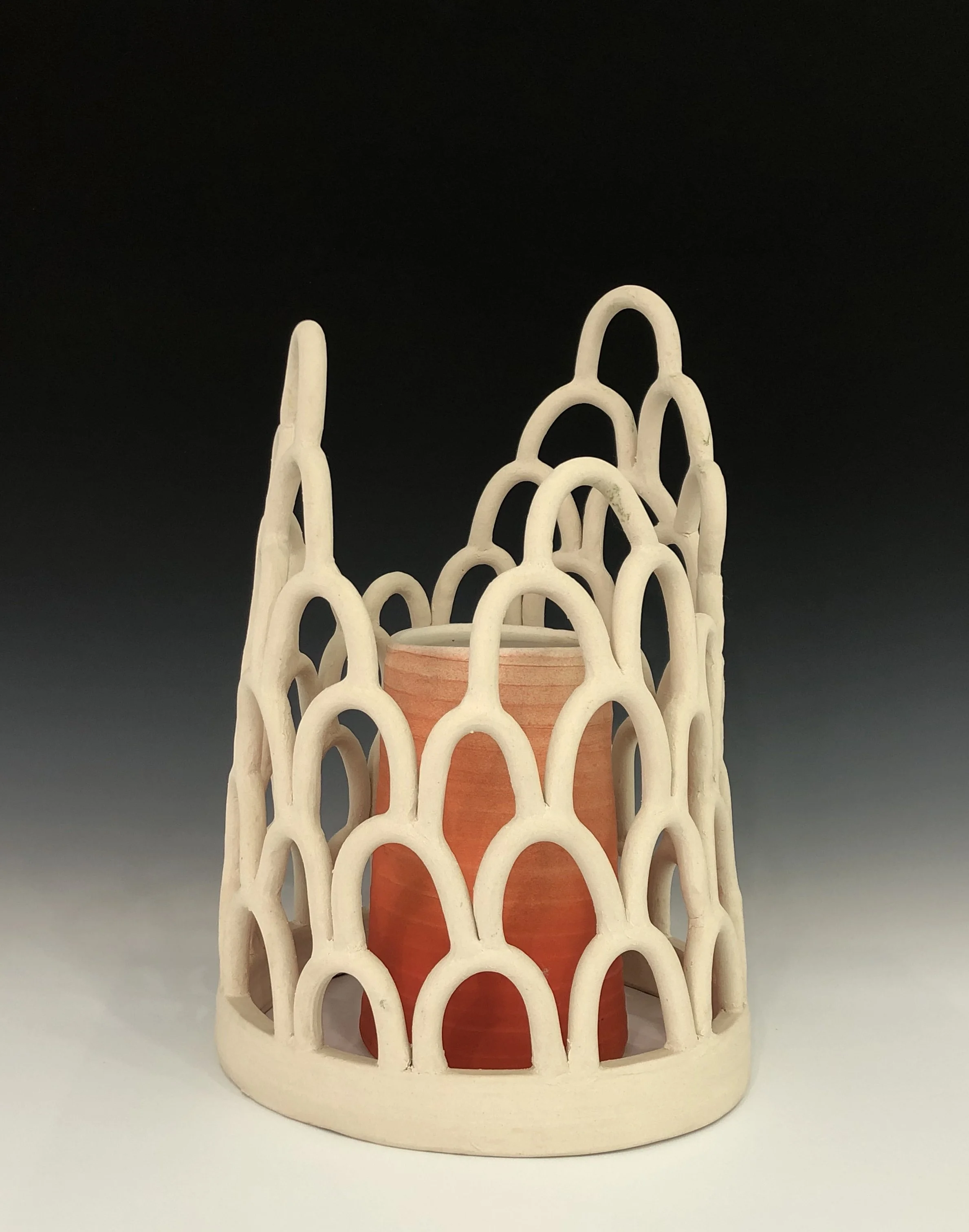 Decorative ceramic cup holder with a lattice pattern and an orange ceramic cup inside.