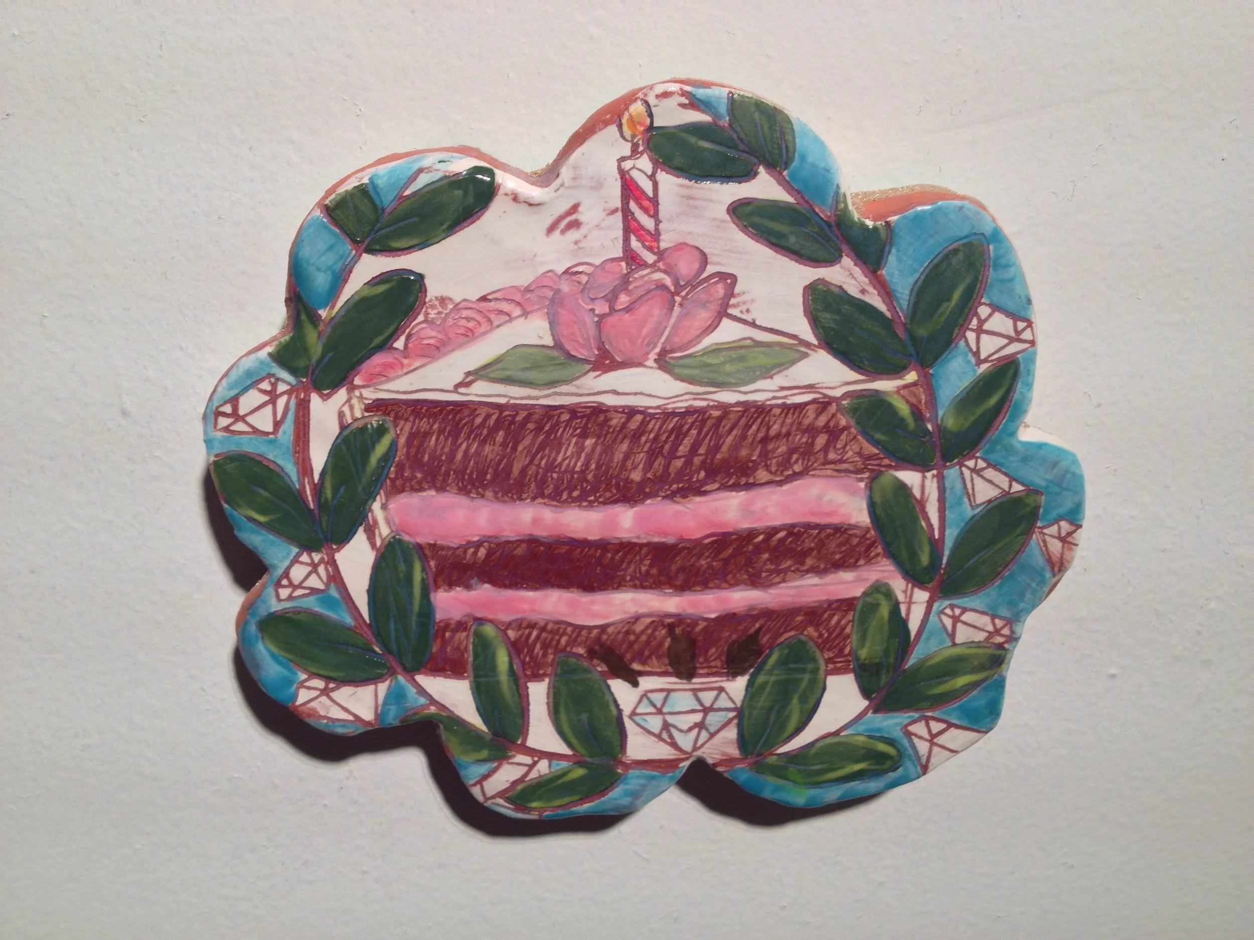 Hand-drawn illustration of a layered pink cake with a cherry and candle on top, surrounded by green leaves and a blue decorative border with diamond patterns.