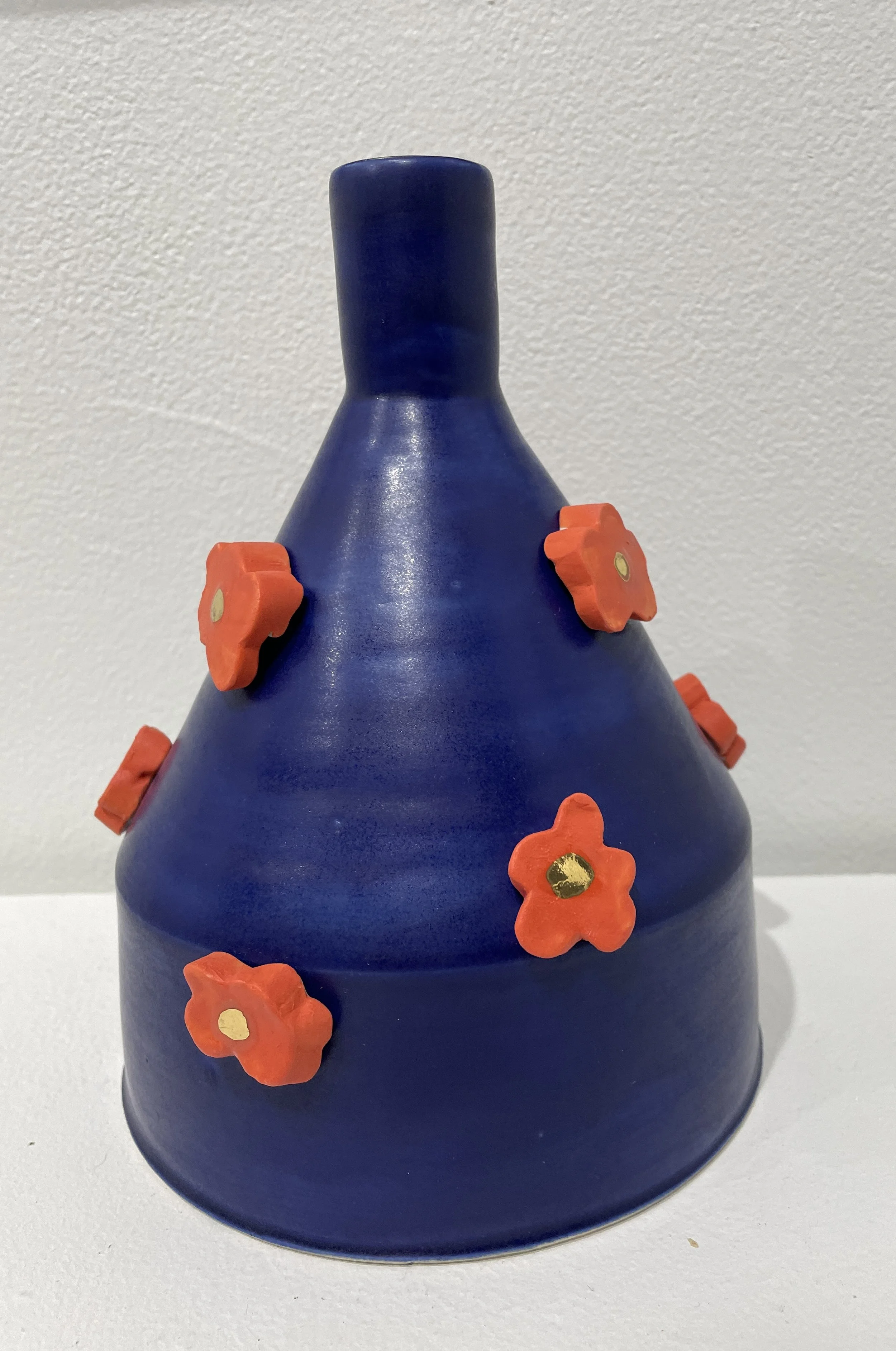 Blue ceramic vase with small orange and gold flower decorations attached to its surface.