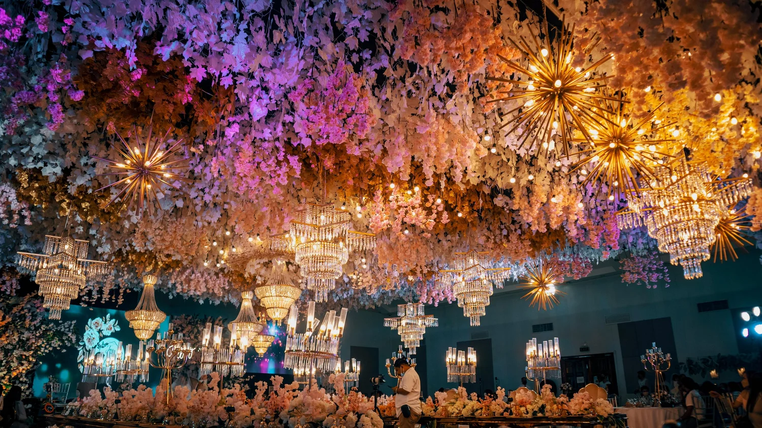 An event room decorated with hanging flowers and chandeliers