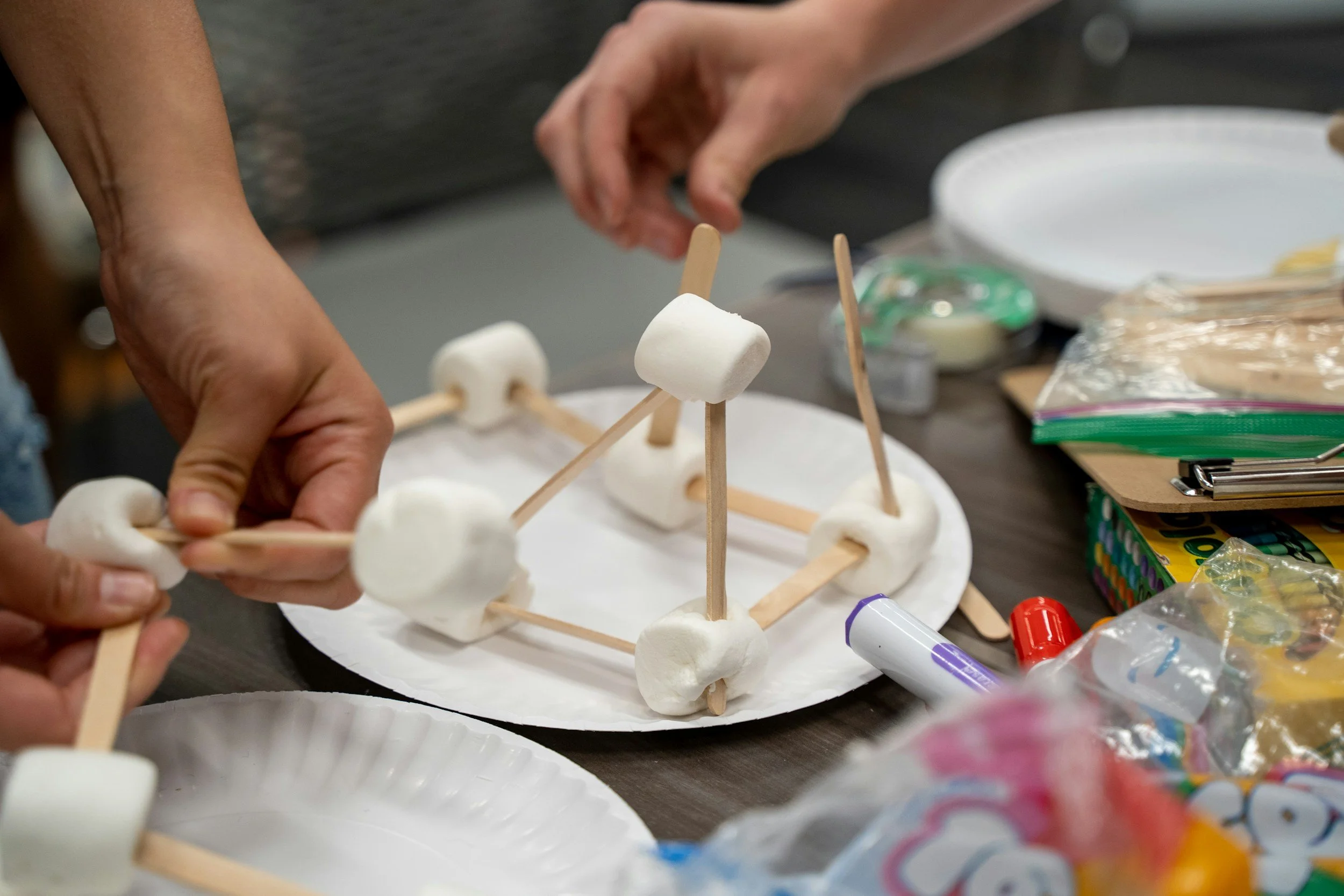 Students at Amma Mountain Academy are participating in a STEAM Design Challenge building with craft sticks and marshmallows.