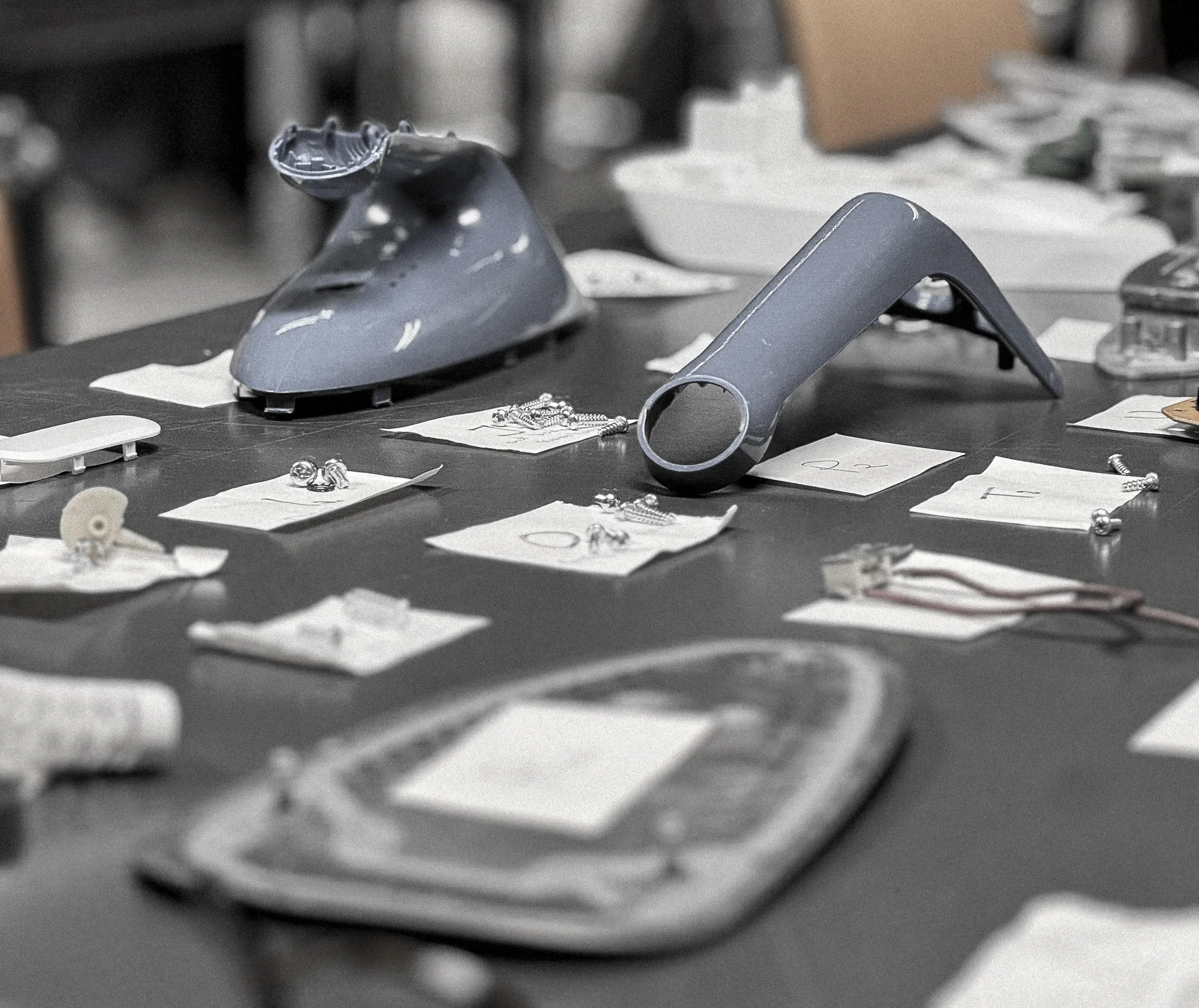 A cluttered work table with an ironing shoe, a handheld steamer, jewelry, watches, and papers scattered across the surface.