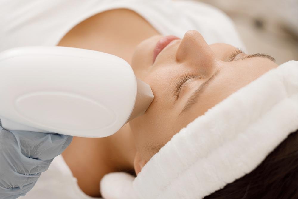 A woman receiving a facial treatment with a ultrasound device in a spa or skincare clinic.