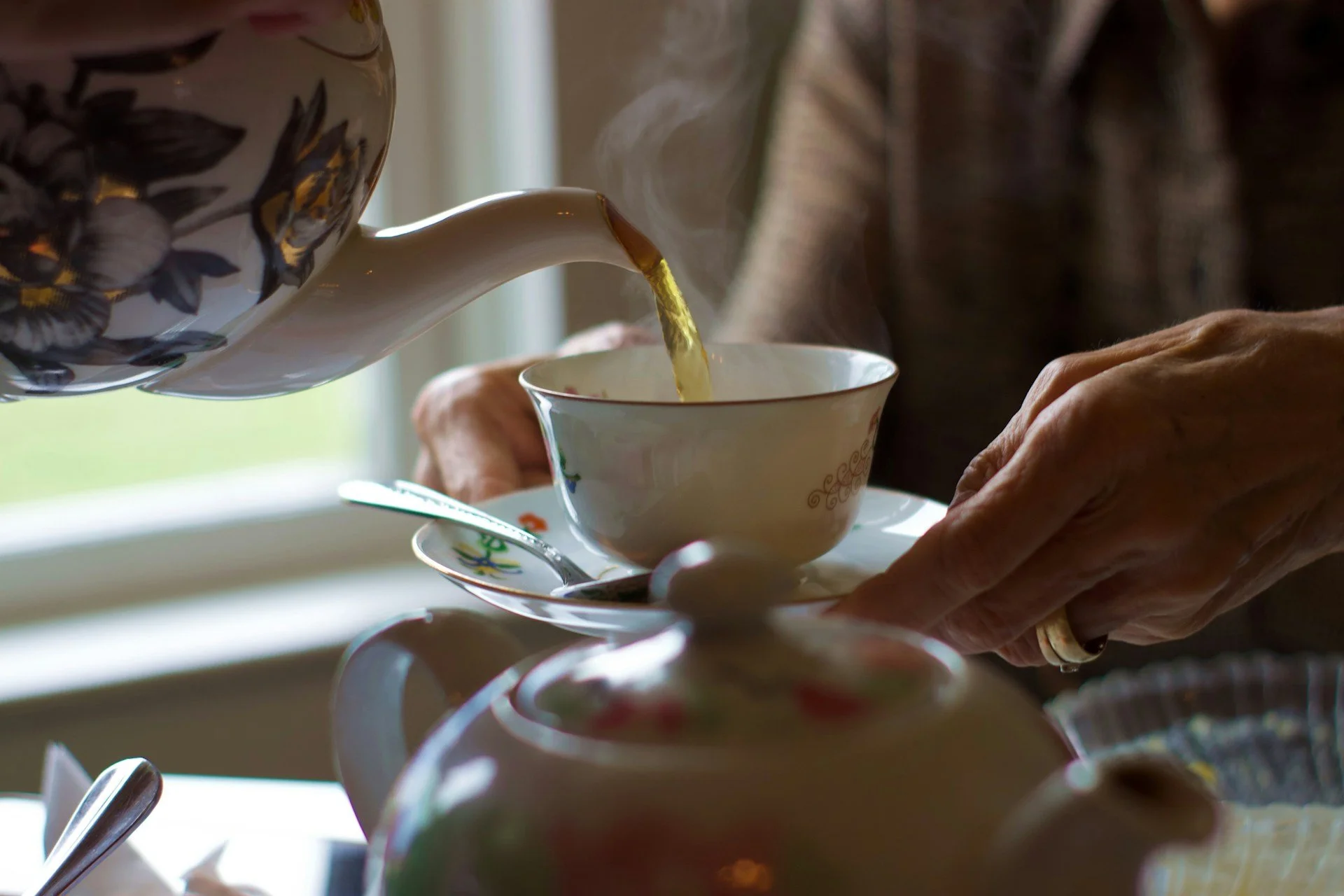 Tea being poured into a cup in a sunlit kitchen, representing in-home companionship and support.