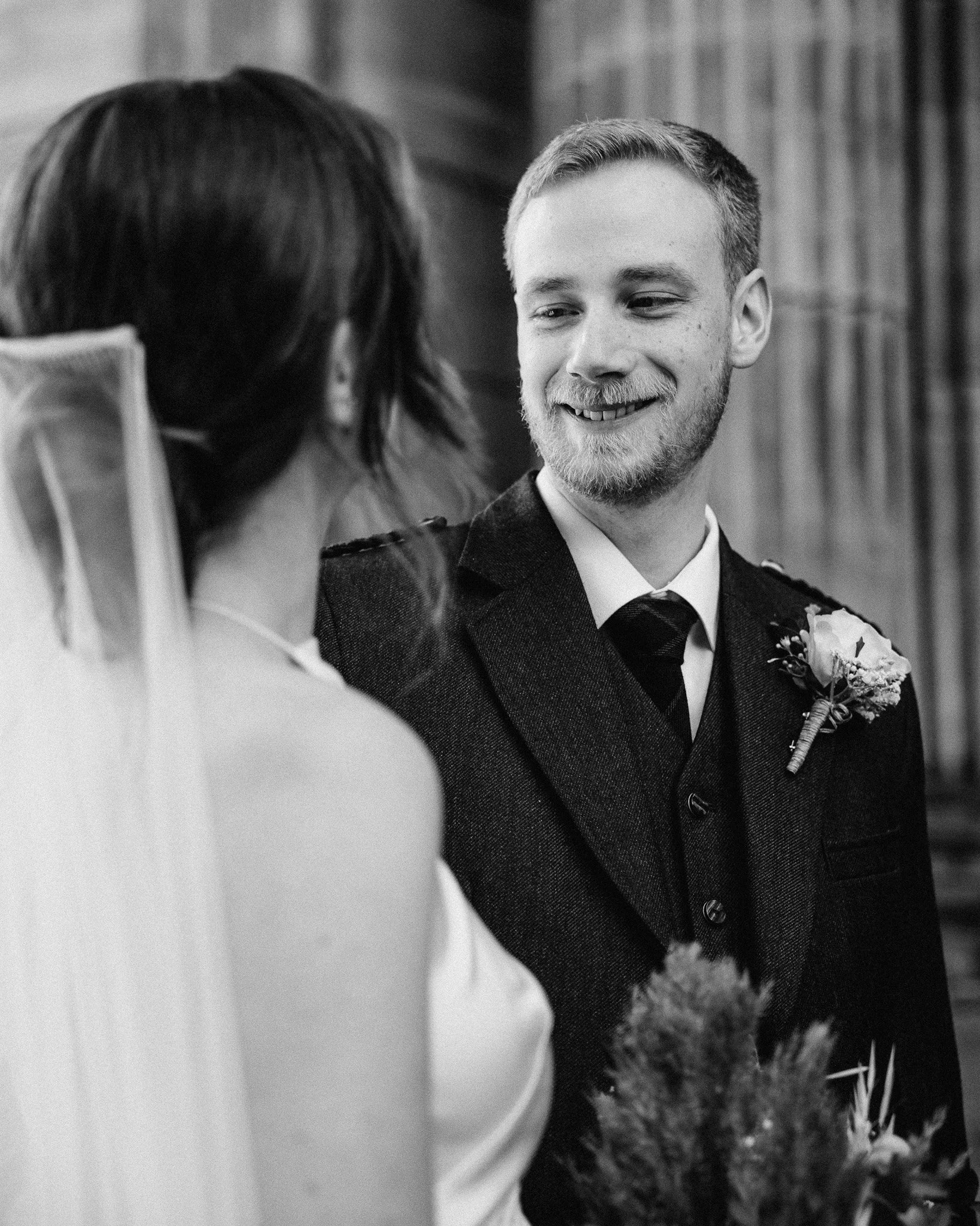 A smiling groom and bride wedding ceremony with the groom looking at the bride.