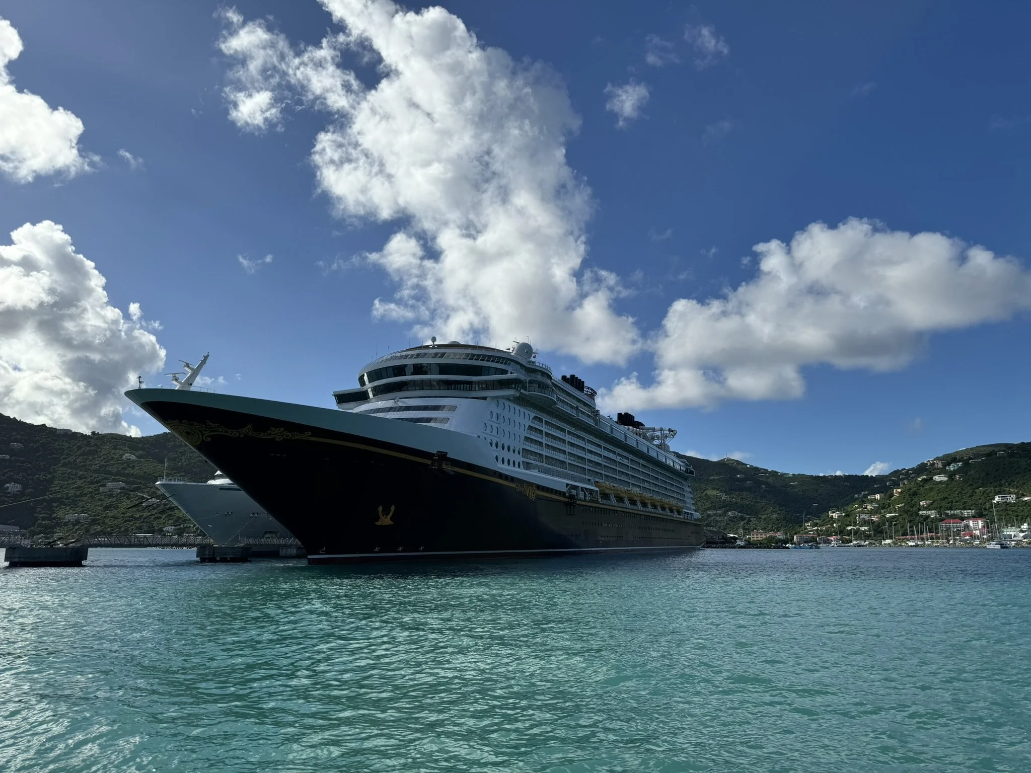 Cruiseship in een haven met bergen en blauwe lucht met wolken.