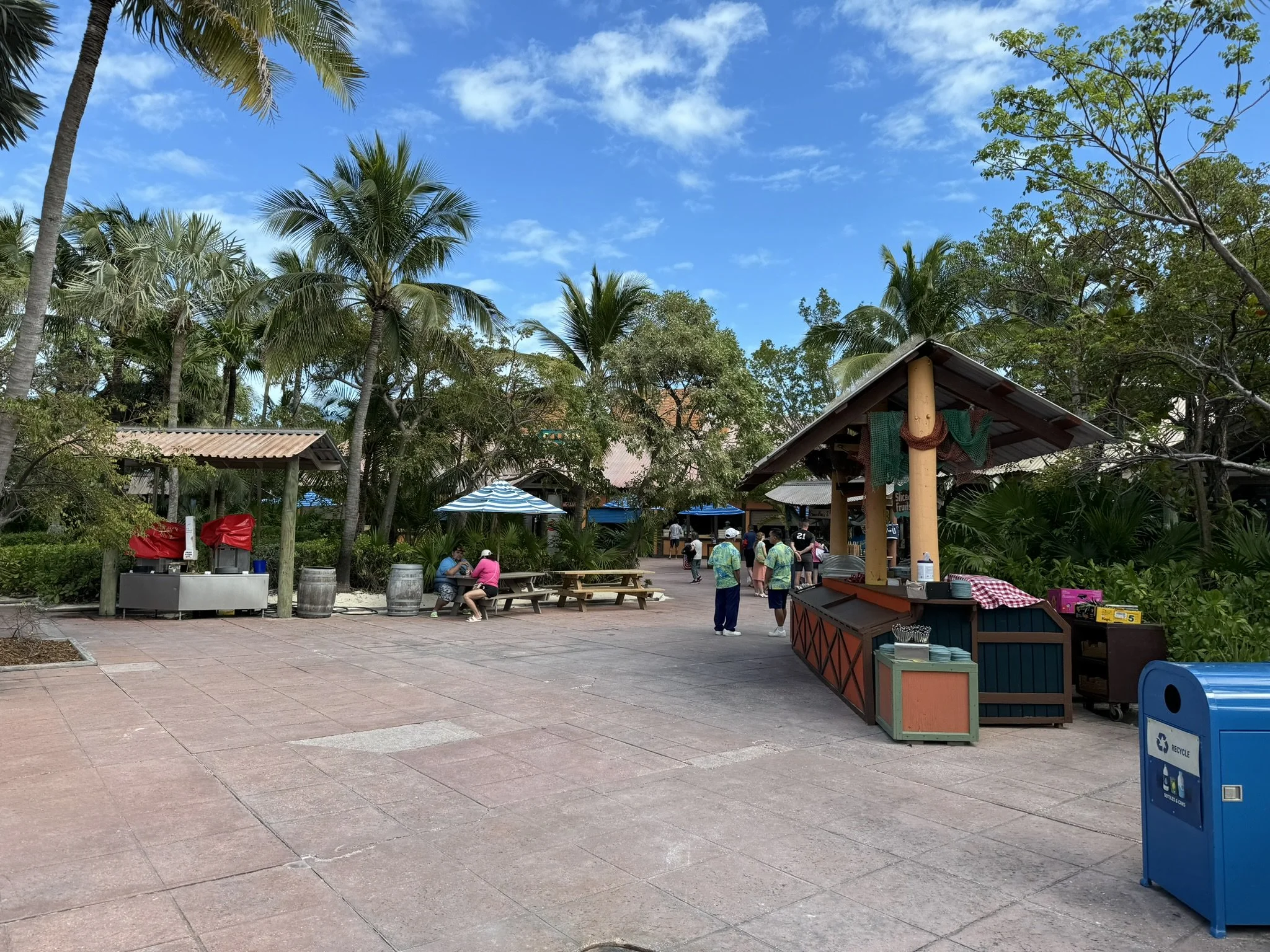 Tropisch eiland met eetkraampje, palmbomen en een blauwe hemel met een paar wolken.