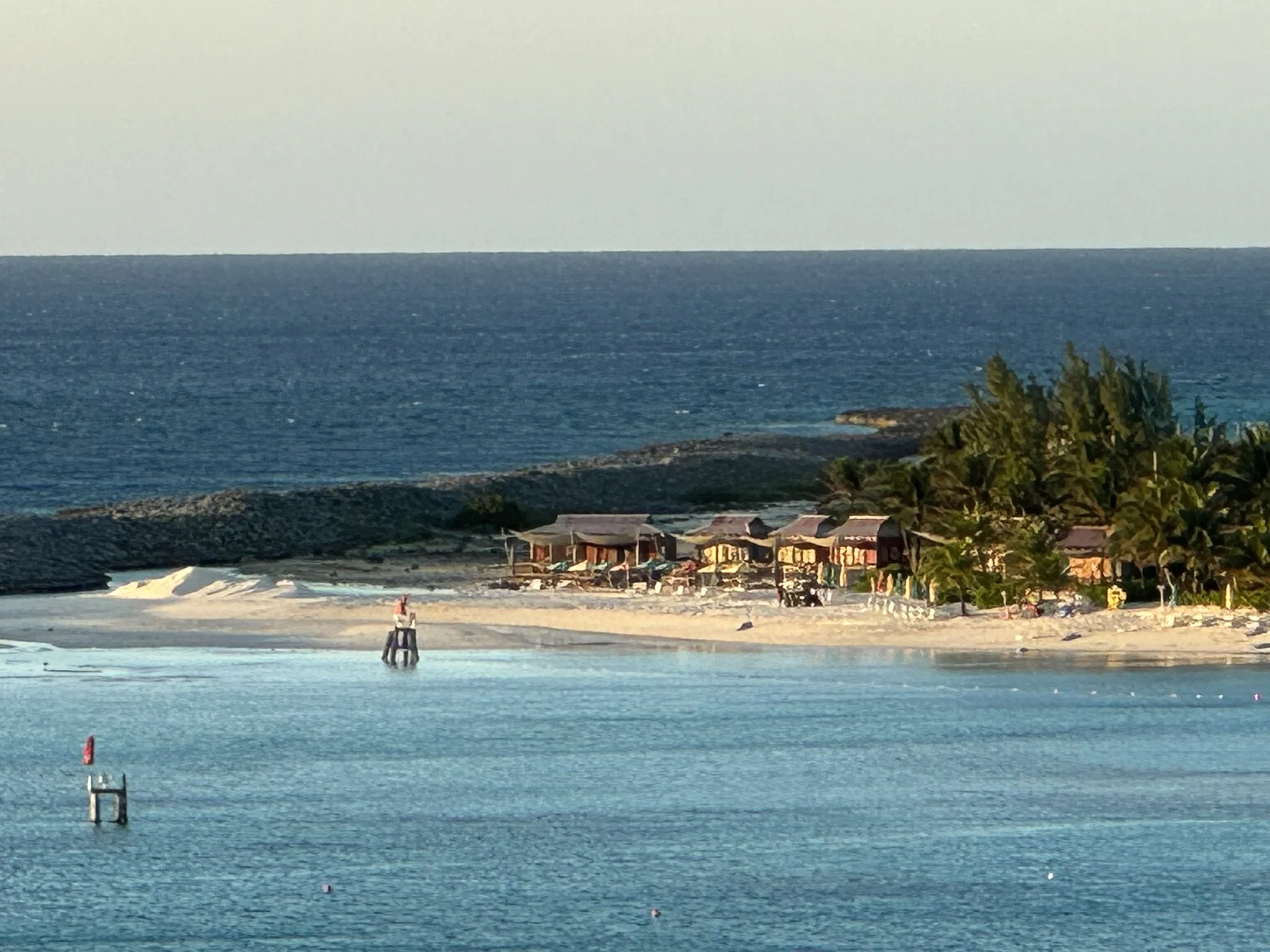 Strand met hutten, palmbomen en de oceaan op de achtergrond in een zonnige omgeving.