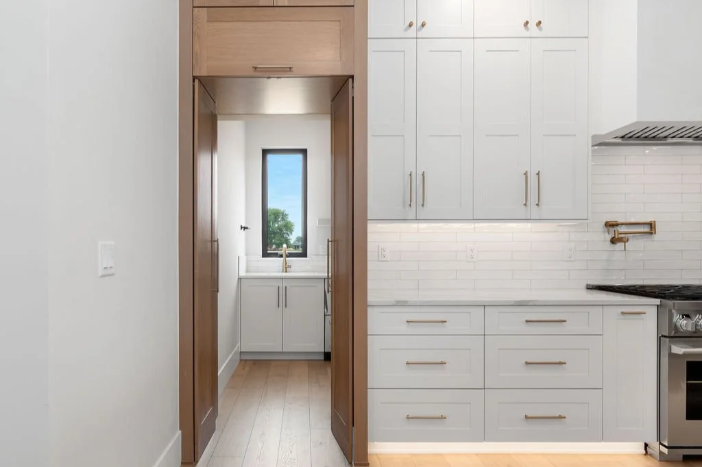 Kitchen with white cabinets, a stove, and a small window at the far end of the room.