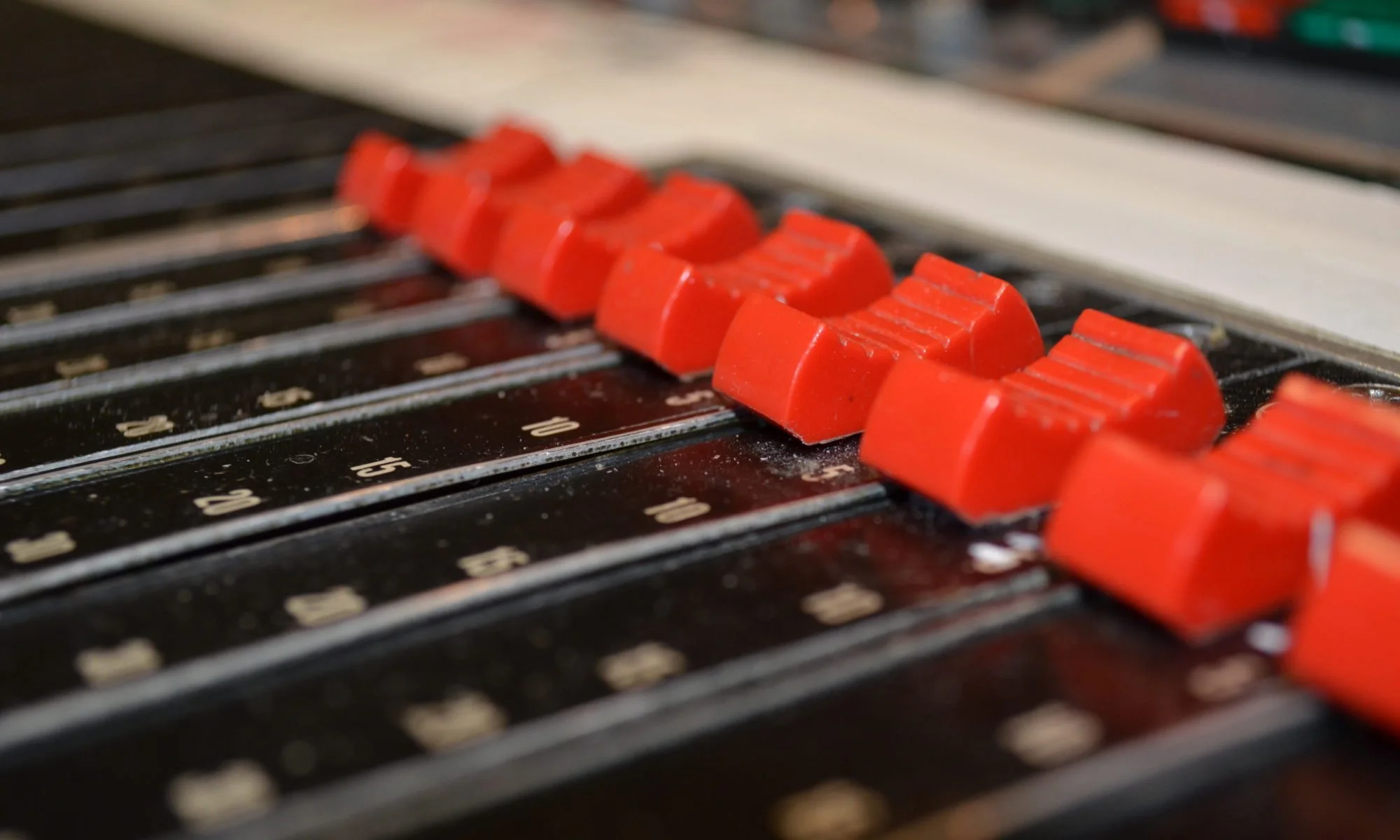 Close-up of orange adjustment knobs on a vintage radio dial, with numbered frequency scale visible underneath.