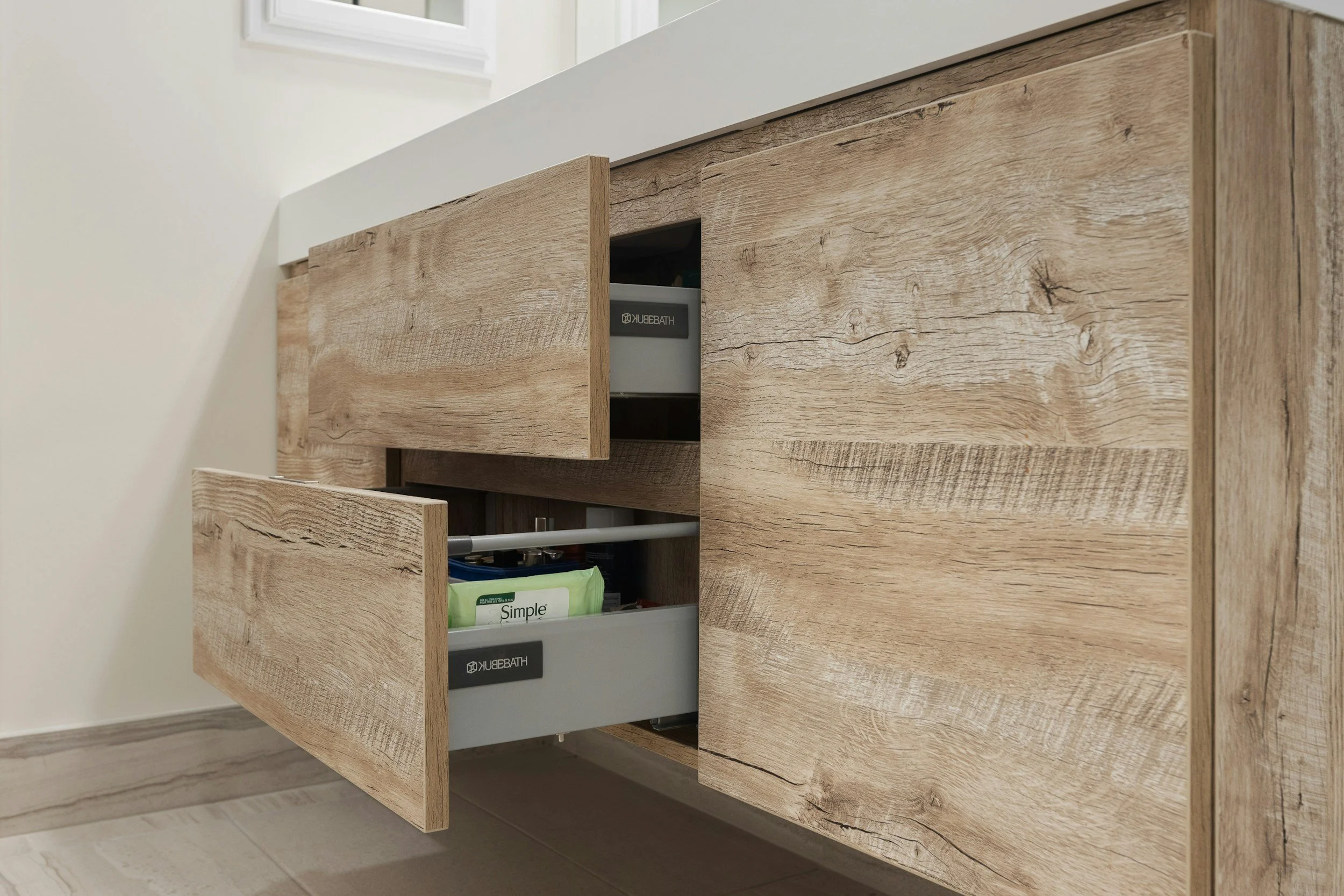 Wooden bathroom cabinet with two open drawers showing storage of toiletries