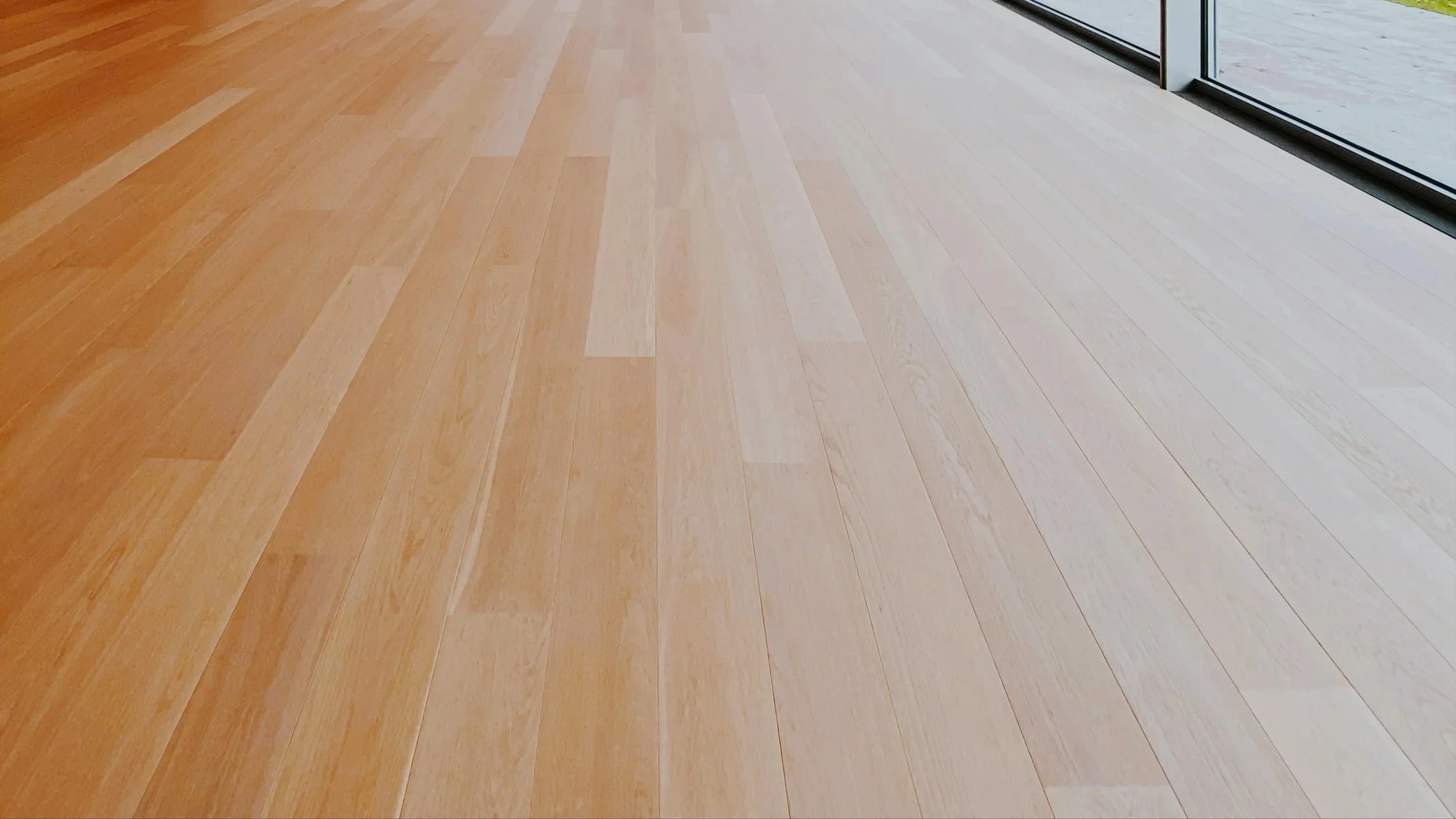 Light-colored wooden floor near floor-to-ceiling glass windows.