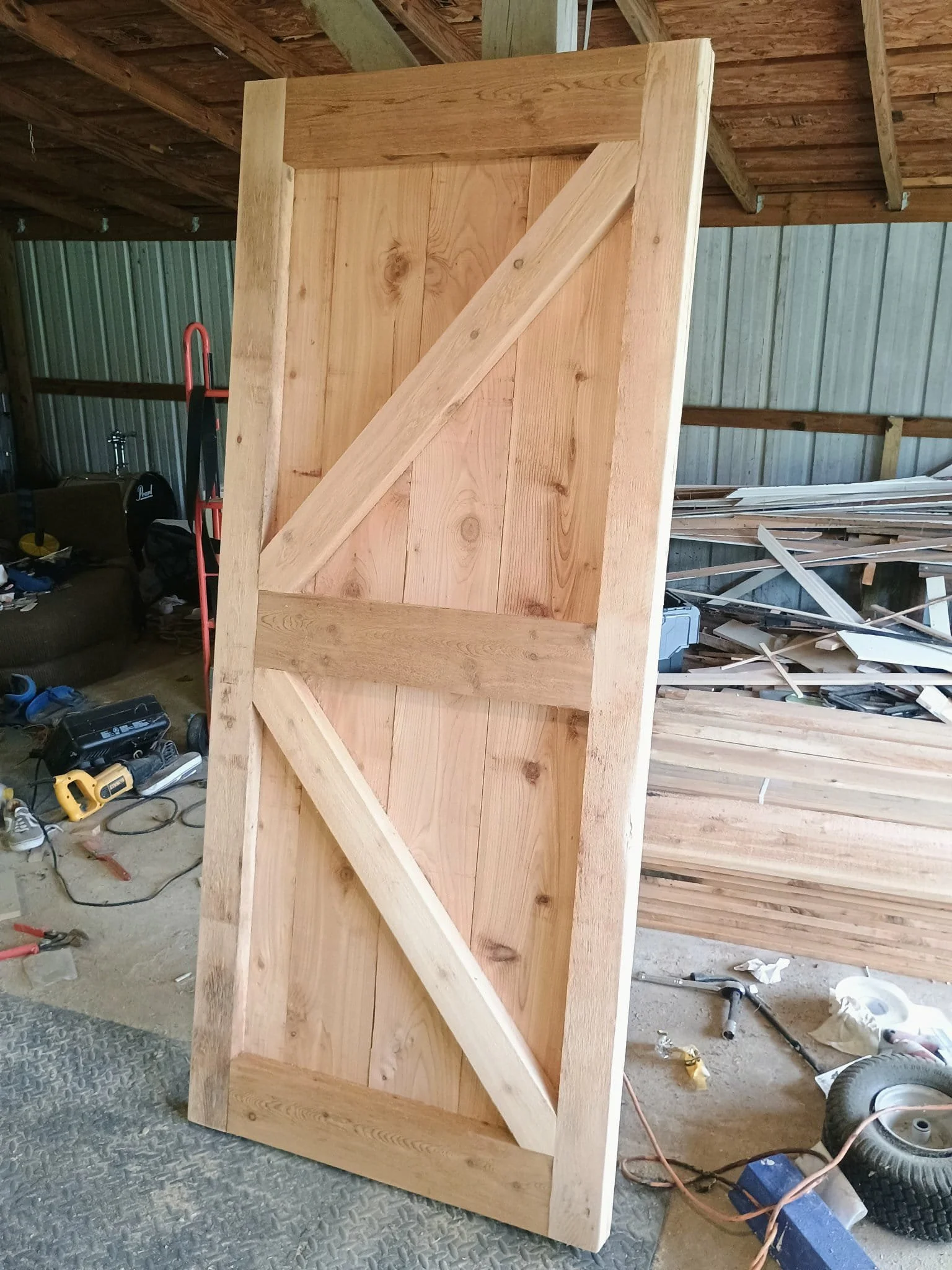 unfinished exterior barn door made of wood with diagonal braces in a workshop