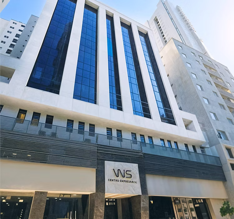 Prédio moderno de escritórios com fachada de vidro azul e entrada principal com sinal de Centro Empresarial WS.