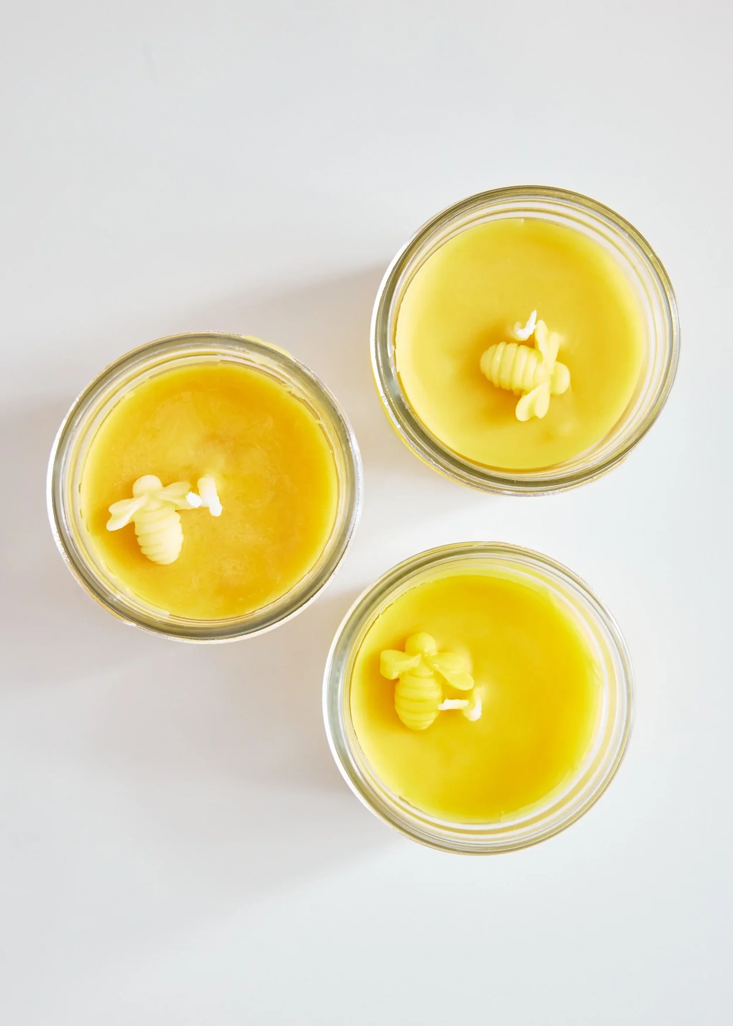 Top view of three glass candles with beeswax wax on a white background.