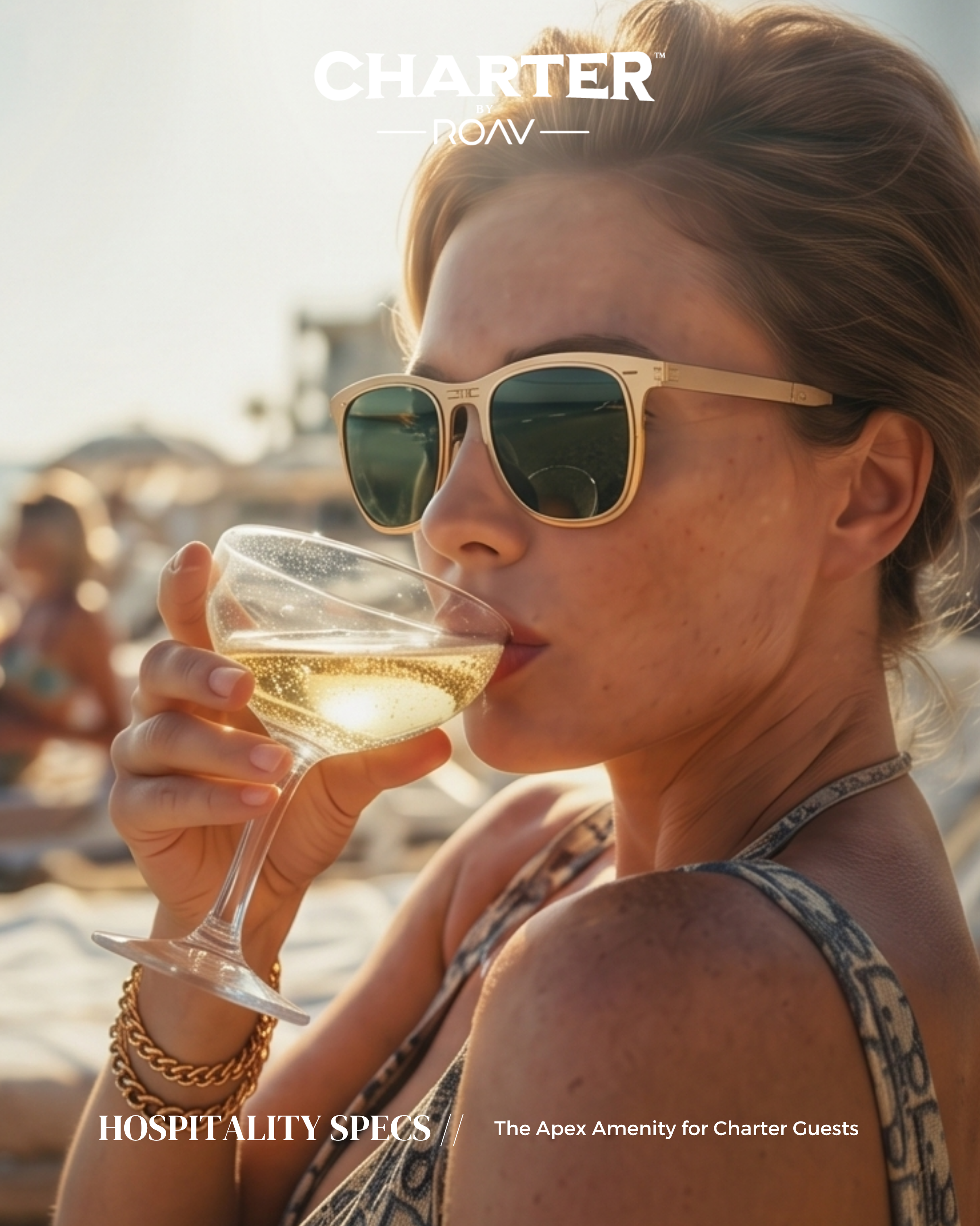 A woman with red hair and sunglasses holding a glass of champagne at a beach party during sunset.