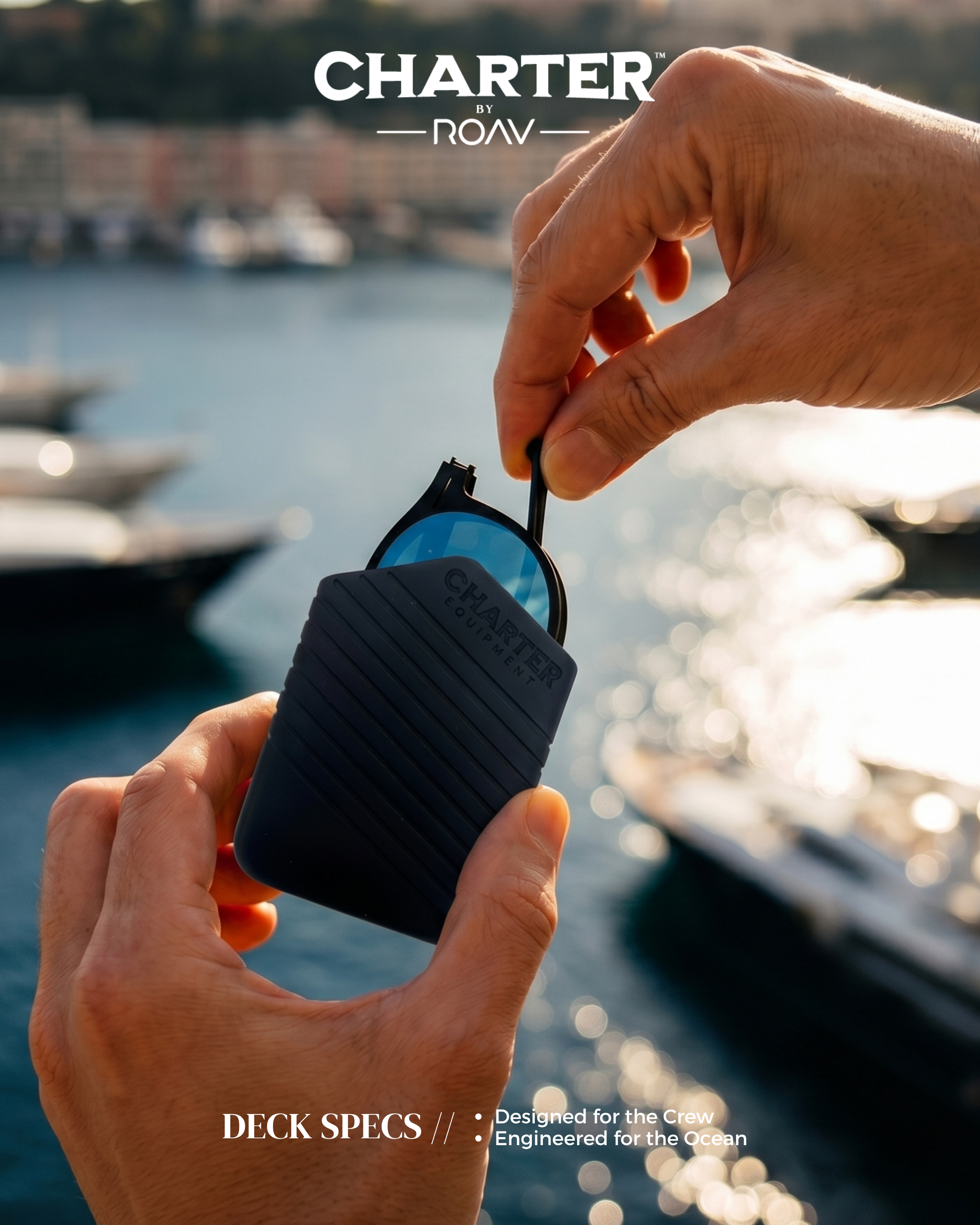 A person holds a pair of sunglasses with a black case labeled 'Chandler Equipment' in front of a marina with boats and water, with the sun reflecting on the water. The overlay text says 'Charter by ROAV' and 'Deck Specs' with additional smaller text.