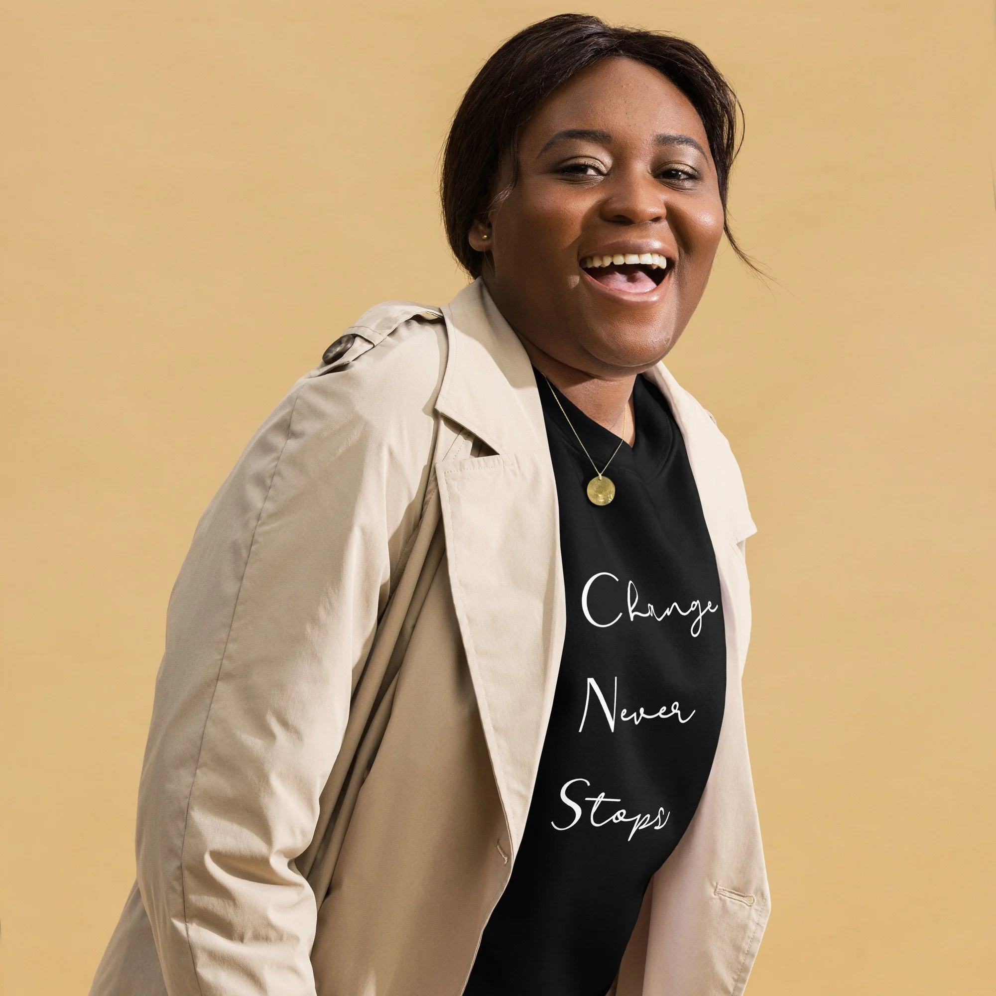 A smiling woman wearing a beige trench coat and a black t-shirt with the words 'Change Never Stops' printed on it, against a yellow background.