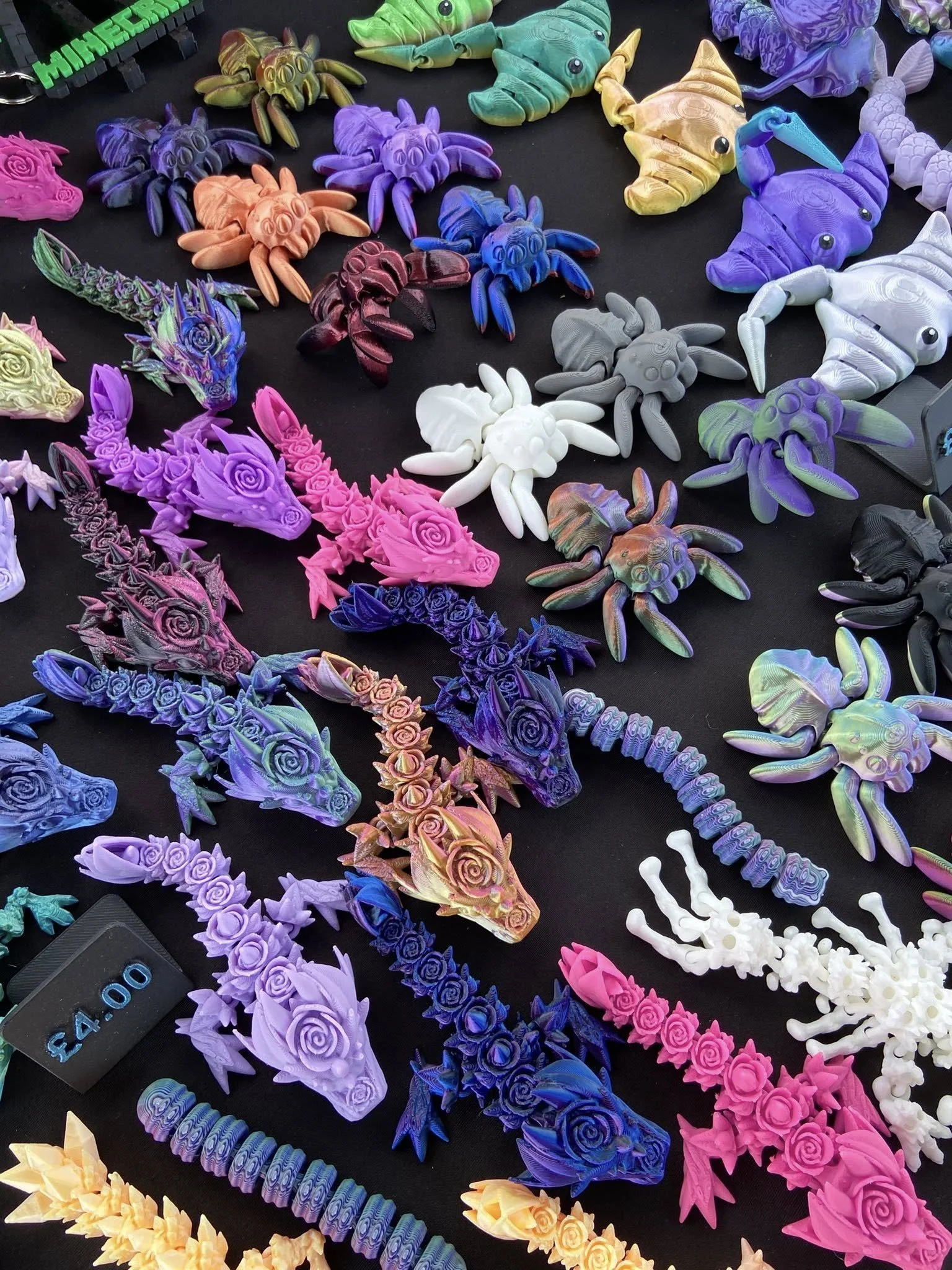 Colorful plastic figurines of various animals including crabs, dragons, lions, unicorns, and other creatures arranged on a black surface for sale, with a price tag of $4.00.