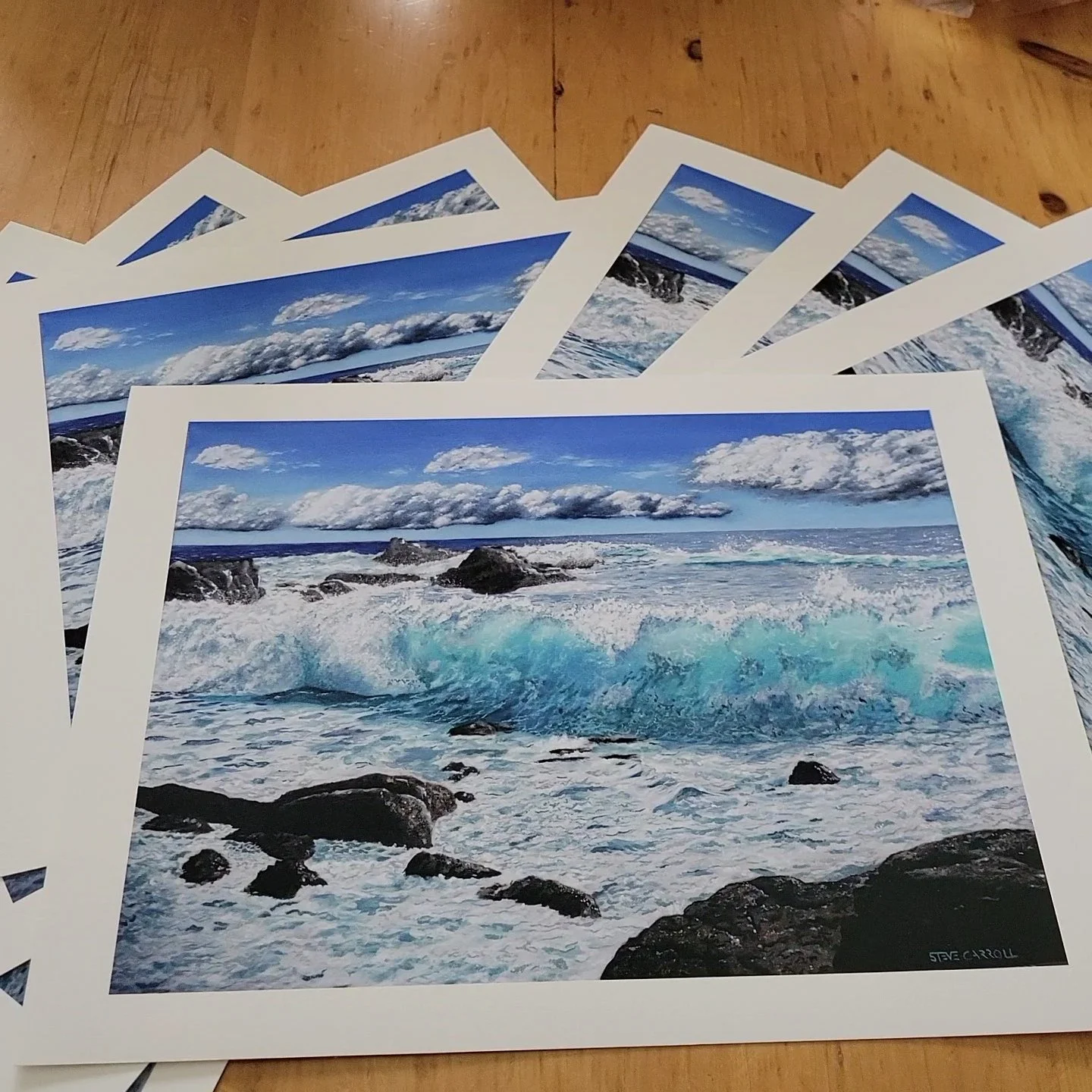 Giclee prints of an oil painting by Steve Carroll depicting rocky shoreline with waves crashing, blue sky with clouds, and the ocean extending to the horizon. The title is Teal I Sea You Again.
