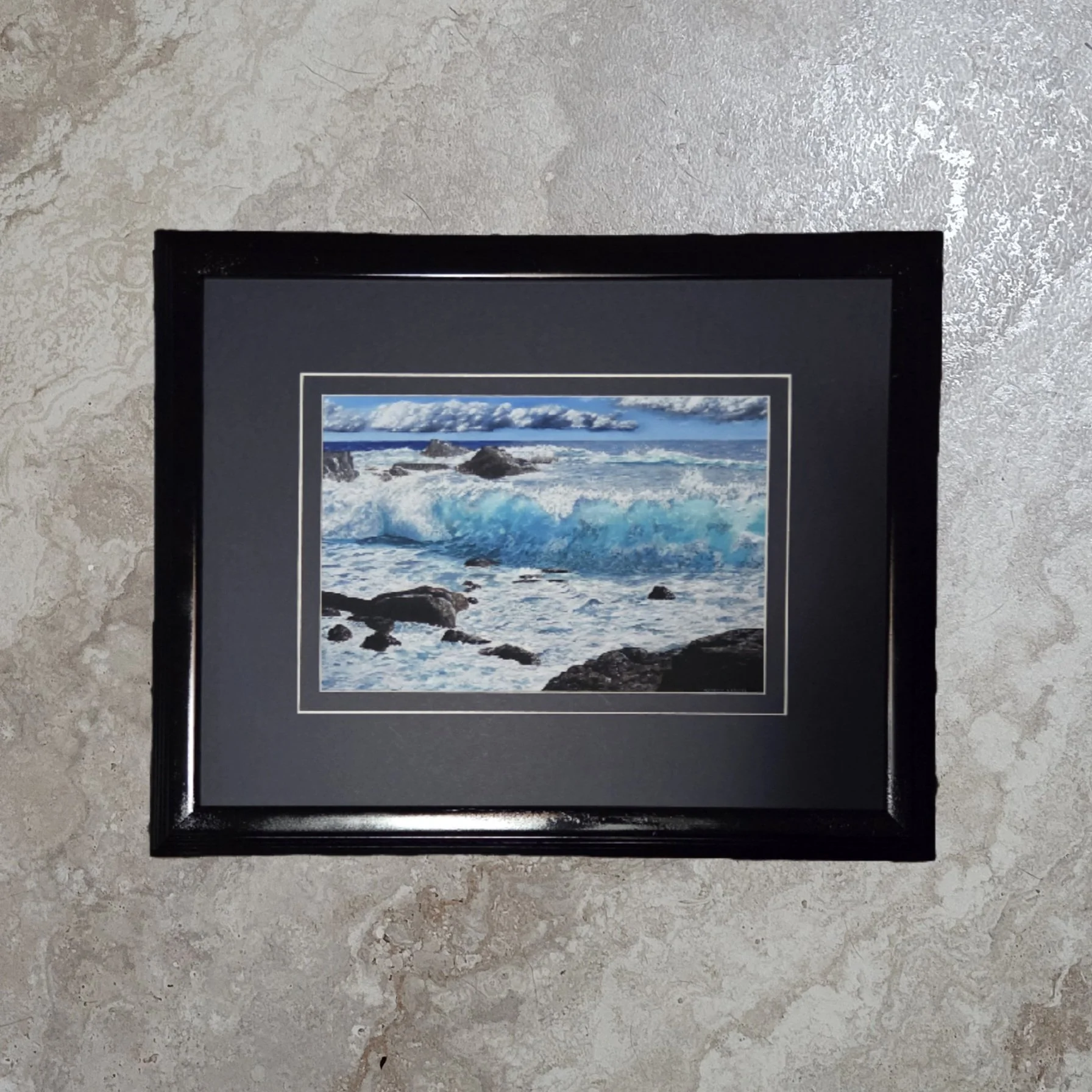 A framed giclee print of artist Steve Carroll's oil painting of an ocean scene with crashing waves and rocks, mounted on a textured wall. The title is Teal I Sea You Again.
