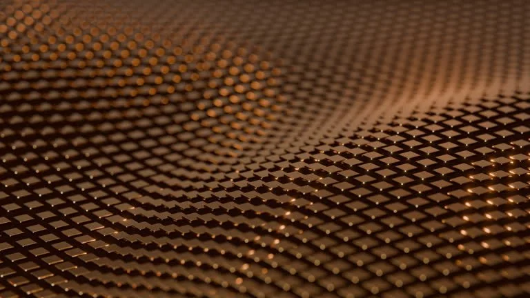 Close-up of a textured, metallic surface with small, raised pyramids creating a pattern, reflecting light.