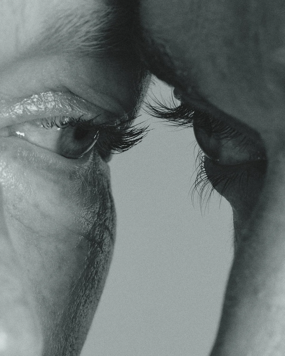 Close-up black and white photo of a person’s face viewed from the side, focusing on the eye and eyelashes, with a contemplative expression.
