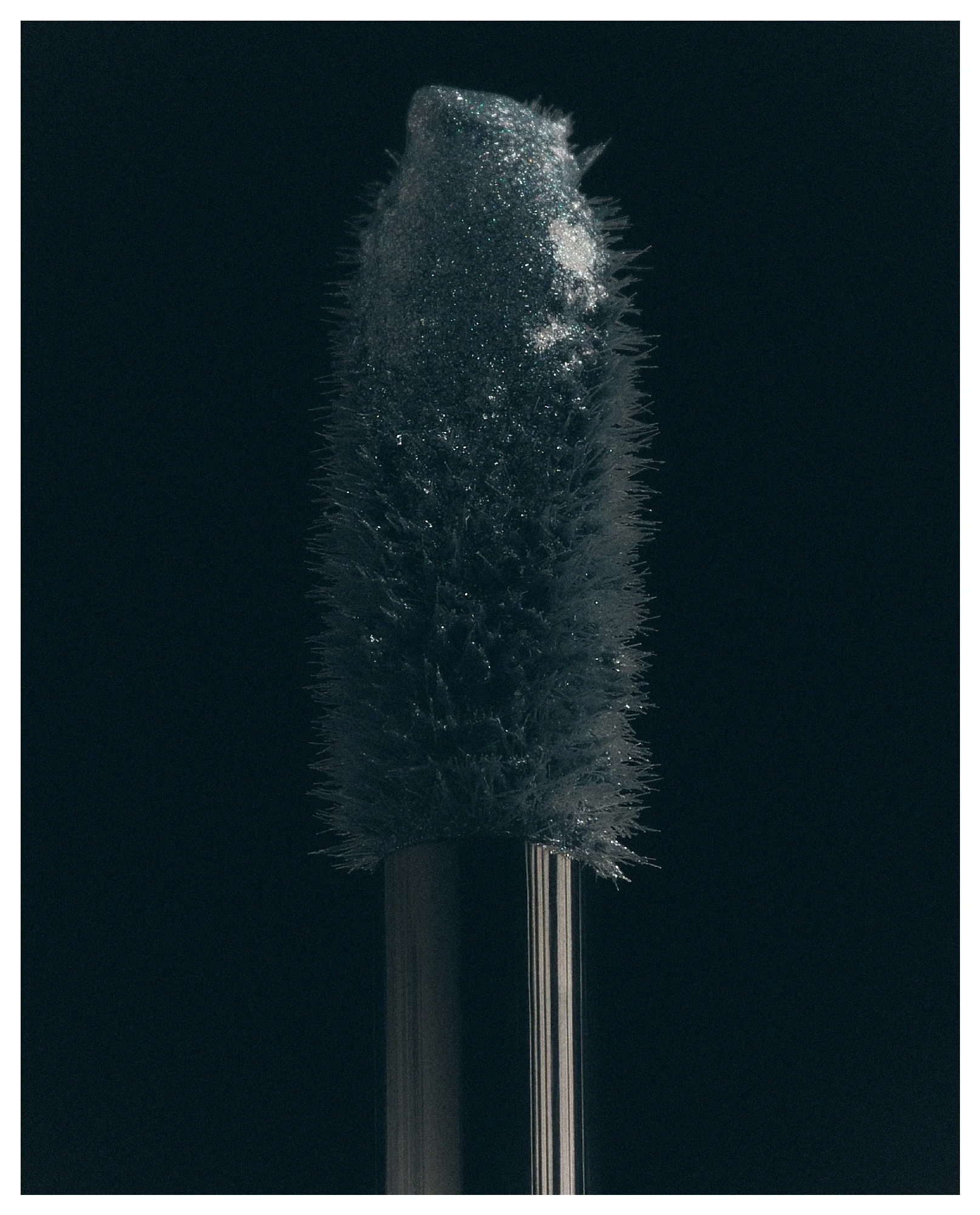 Cleaning brush with a long handle and a rounded, spiky brush head, set against a dark background.