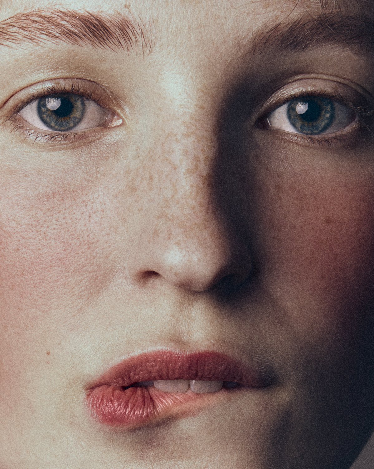 Close-up of a woman's face showing her blue eyes, freckles, light skin, and lips.