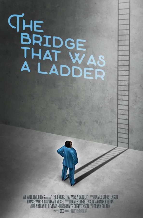 A person in a blue suit looking up at a large concrete wall with a ladder painted on it. The wall has the phrase "The Bridge That Was a Ladder" written in large blue letters.