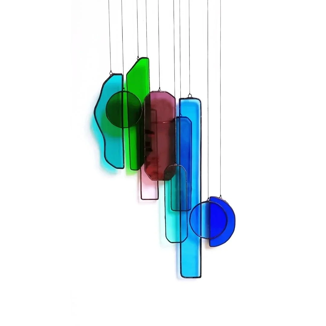 Suspension en verre coloré style moderne avec des formes géométriques suspendues par des fils noirs. Création mobile en vitrail dans l'atelier de Diane à Lille. Venez créer votre mobile et découvrez toutes les étapes du vitrail Tiffany.