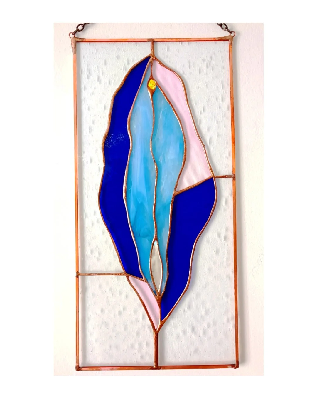 Vitrail abstrait avec formes ondulantes en couleurs bleue, rose et transparentes, encadré en cuivre