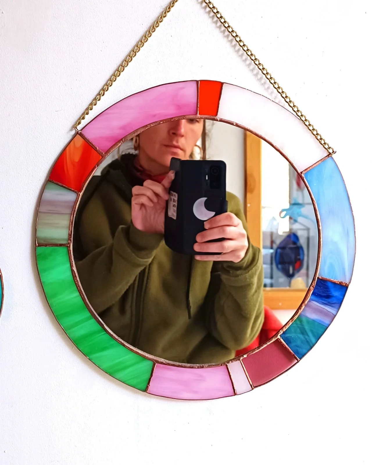 Un miroir rond en vitrail accroché au mur de l'atelier de Diane Frank, à Lille. Atelier de créations sur demandes, à Lille.
