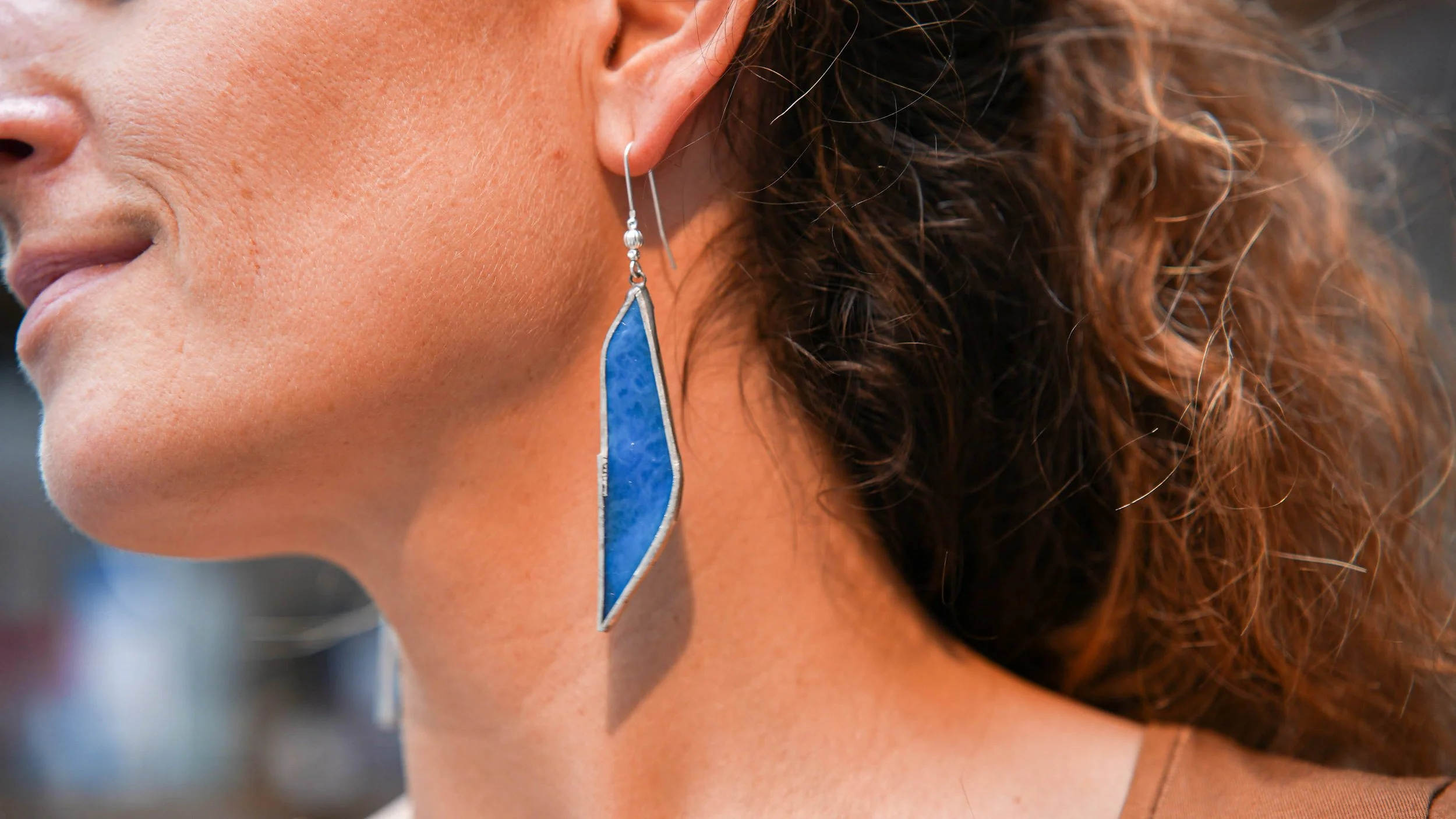 Atelier bijoux
Boucle d'oreille en forme de triangle avec une face en verre bleu, suspendue à une oreille d'une participante de l'atelier création de boucles d'oreilles en vitrail Tiffany. Atelier de 2h30 dans l'atelier de Lille, Le vitrail de Diane.