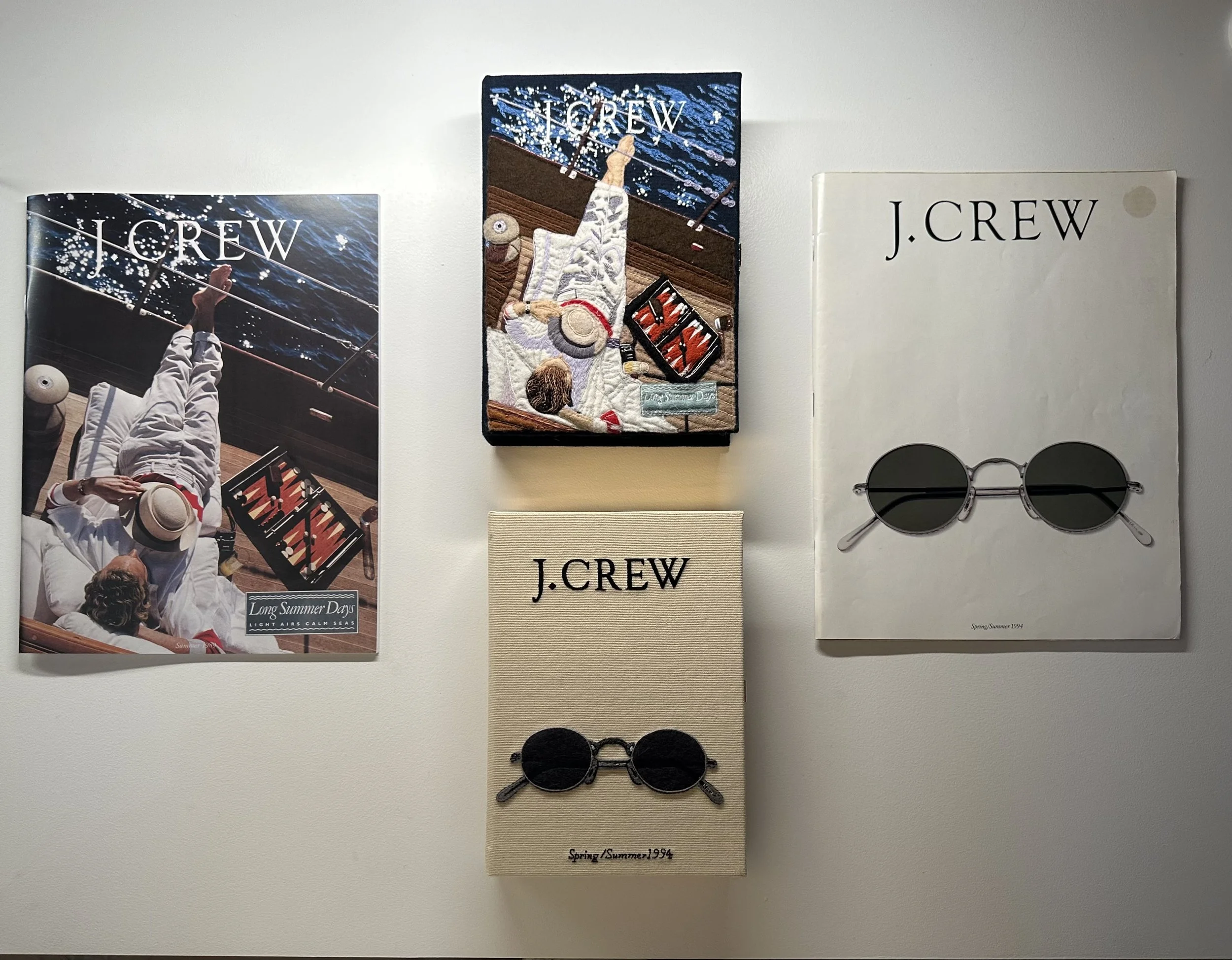 Display of J.Crew sunglasses with various promotional materials on a wall, including posters and fabric-covered boxes.