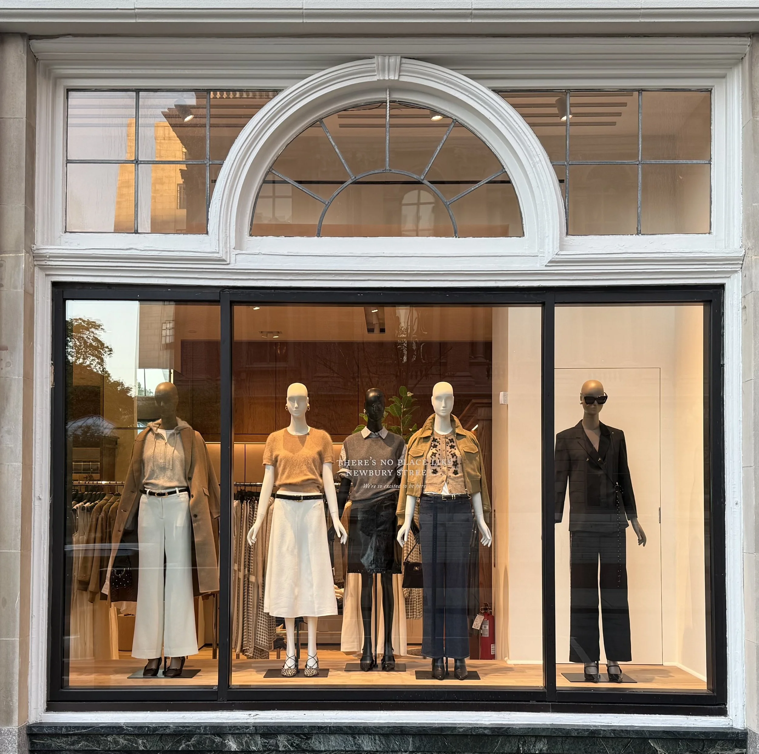 Display window with mannequins showcasing fashion outfits in a clothing store.