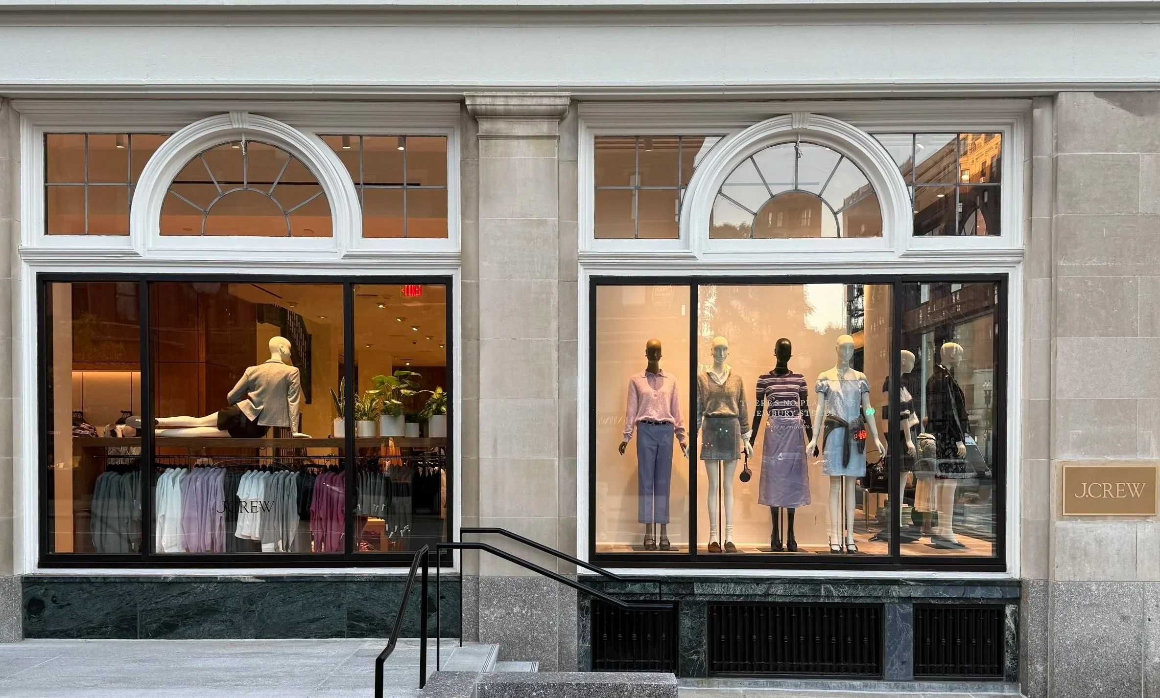 Storefront window display of J.Crew with mannequins dressed in women's clothing and a neatly arranged collection of shirts.