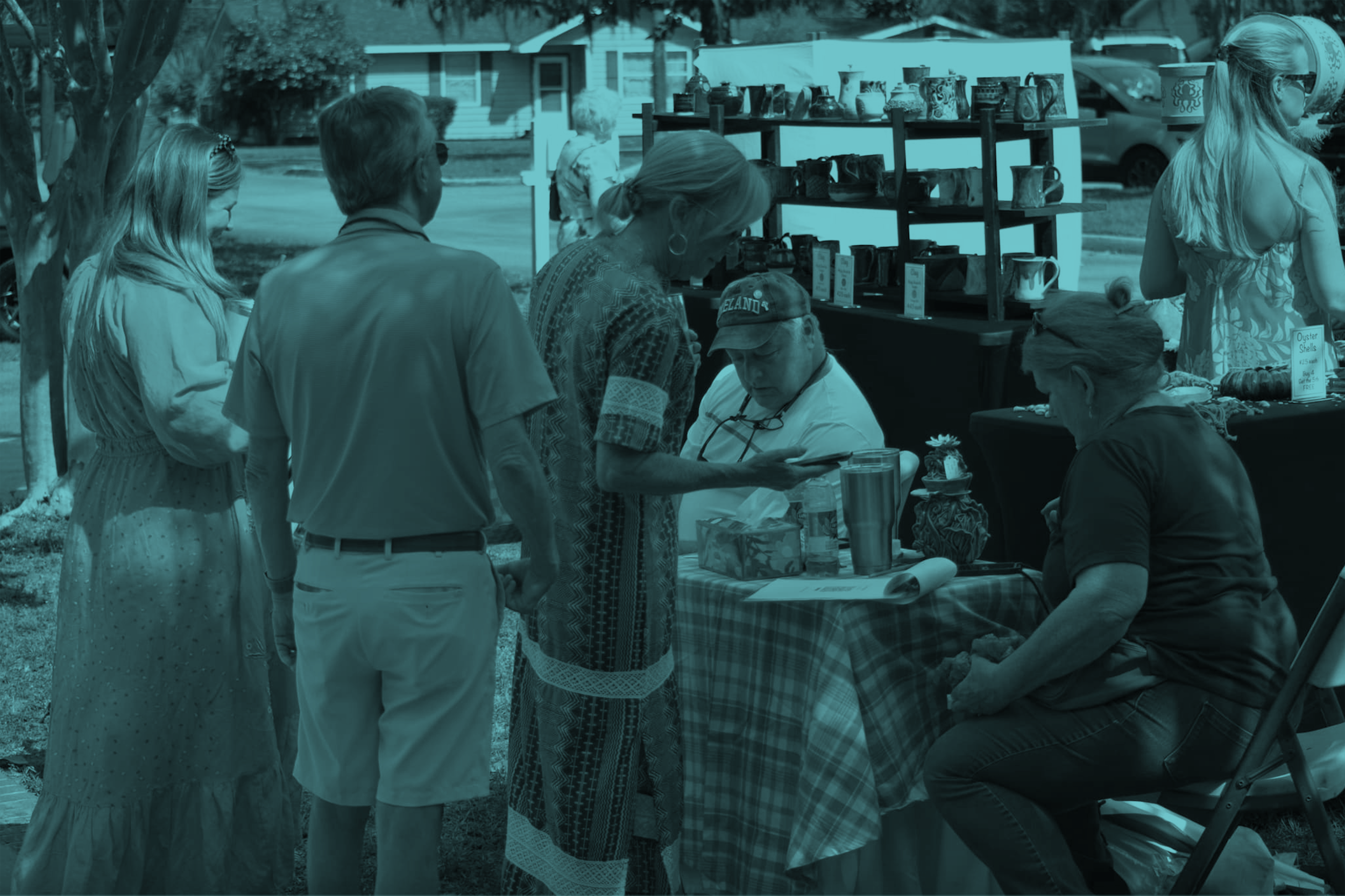 People browsing at an outdoor craft fair or market with stalls selling pottery and other items.