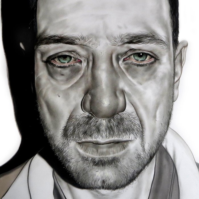 Close-up portrait of a man with a tired and expressionless face, showing signs of fatigue or distress, with a shadowed background.